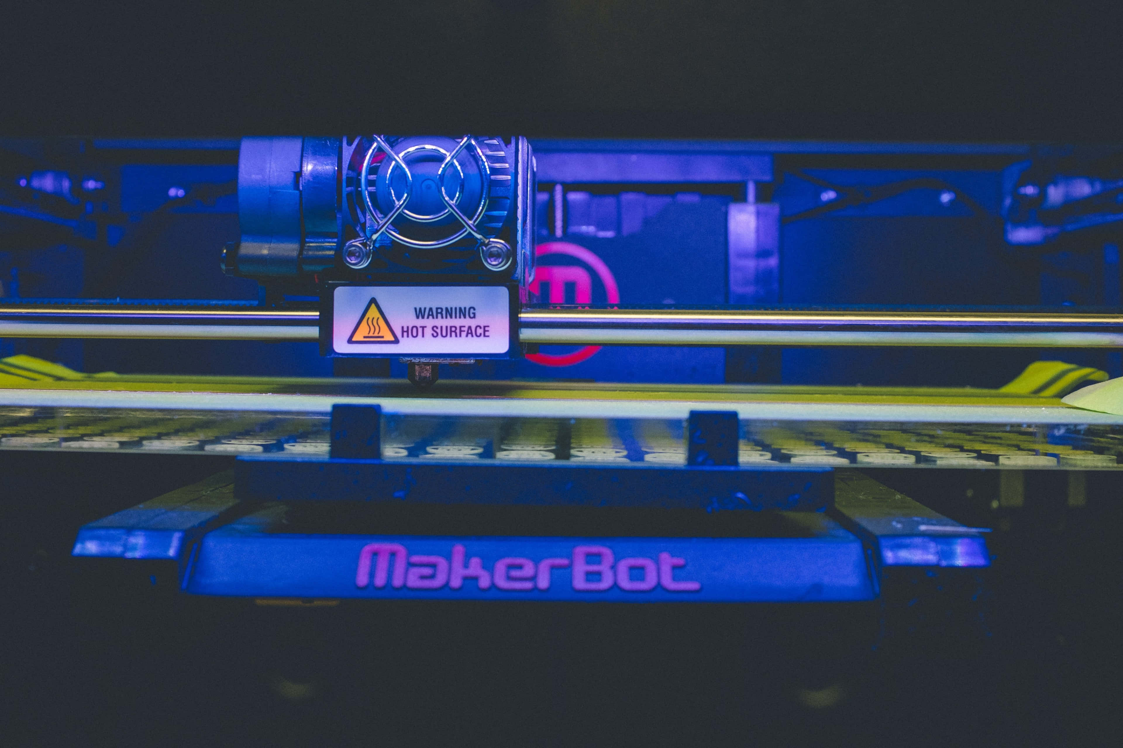 3d Printer 桌布 壁紙 — MakerBot 3D印表機在藍光下發光，其高溫表面帶有警告標籤。