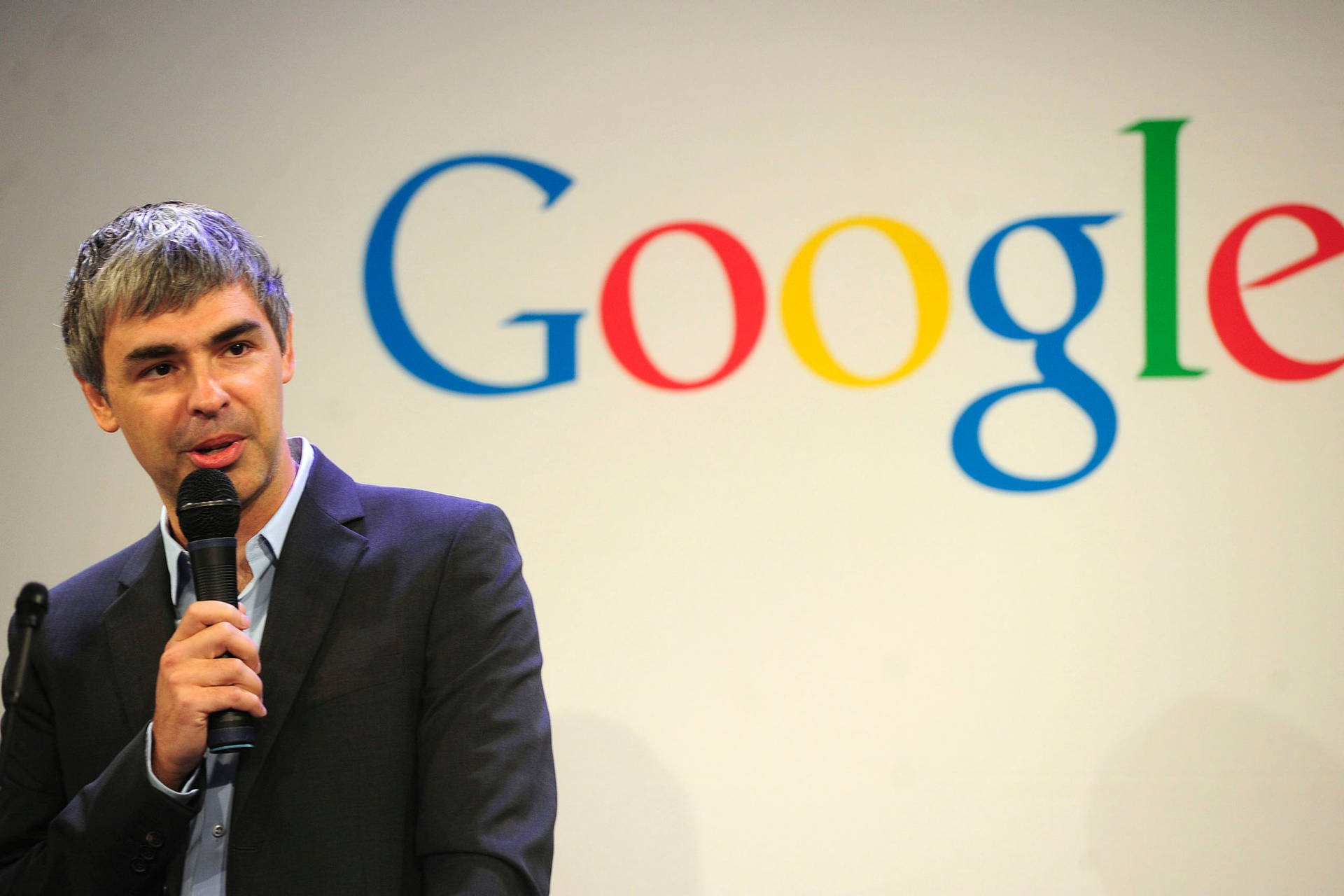 身穿西裝的男子在Google活動中對著麥克風講話。 — Google 壁紙