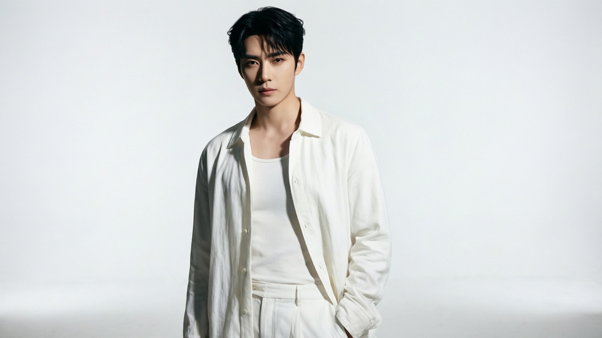 White Minimalist Elegance 壁紙 — 一個黑髮男人穿著敞開的白襯衫和白褲子，背景是純白色。