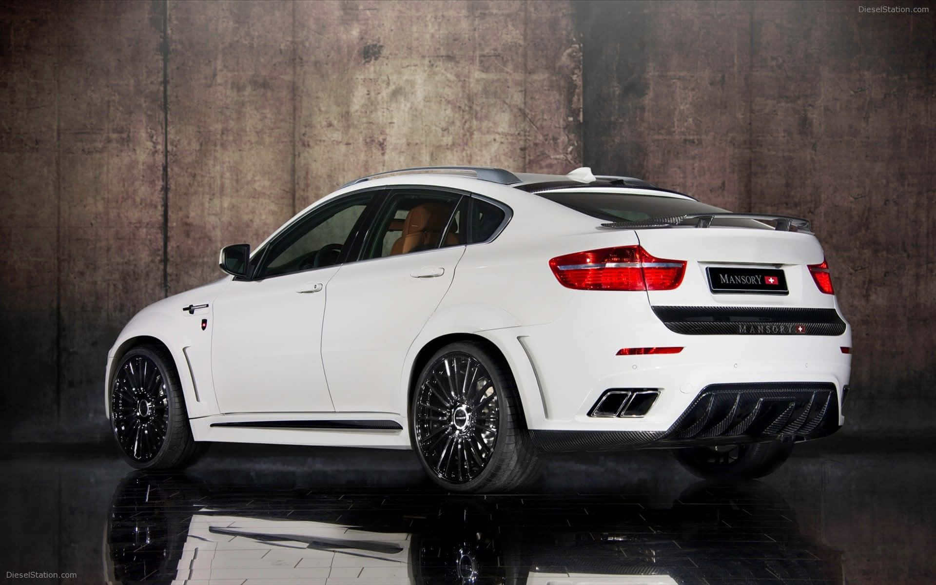 Bmw X6 桌布 壁紙 — 一輛純白色的Mansory改裝BMW X6在攝影棚燈光下，以紋理混凝土牆和光澤地板反射為背景閃耀。