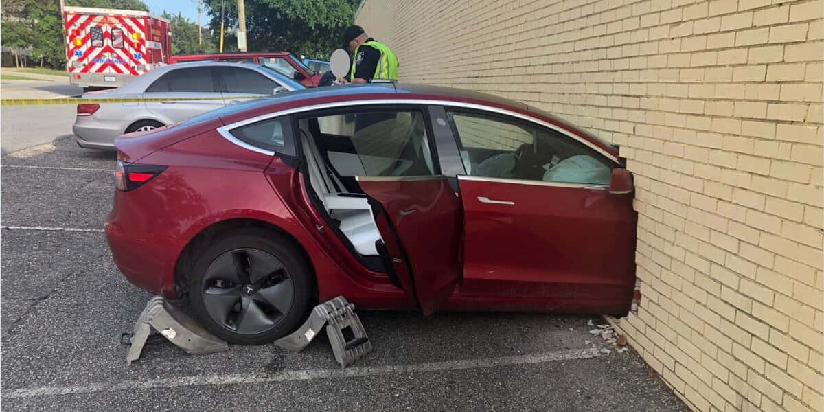 Tesla Model Y 桌布 壁紙 — 一輛栗色Tesla轎車撞上米色磚牆，車門敞開，應急人員在附近。