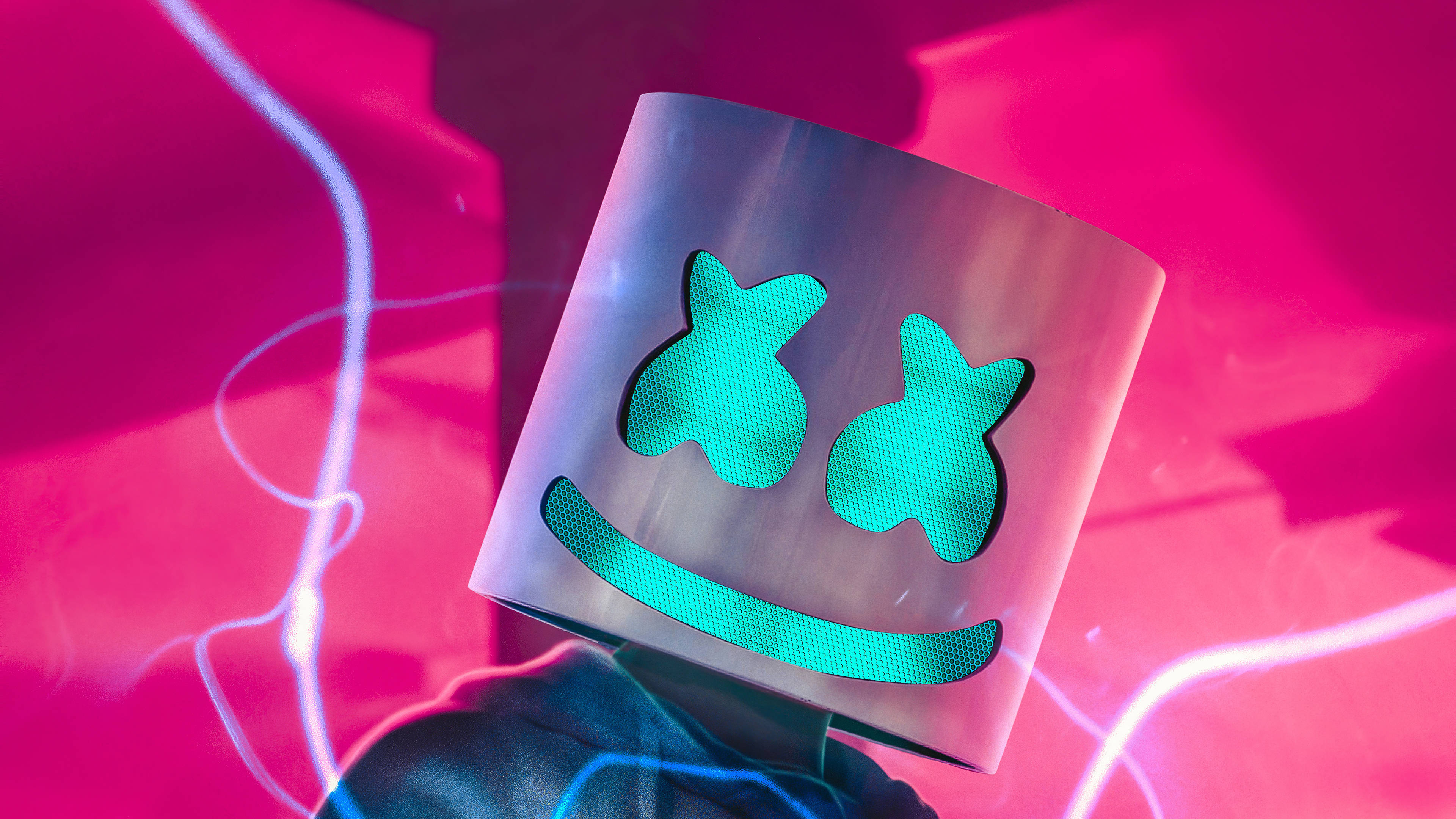 Marshmello 4K 桌布 壁紙 — Marshmello 標誌性半透明頭盔的特寫，在充滿活力的粉紅色霓虹燈背景下，散發著藍綠色眼睛和微笑的光芒。