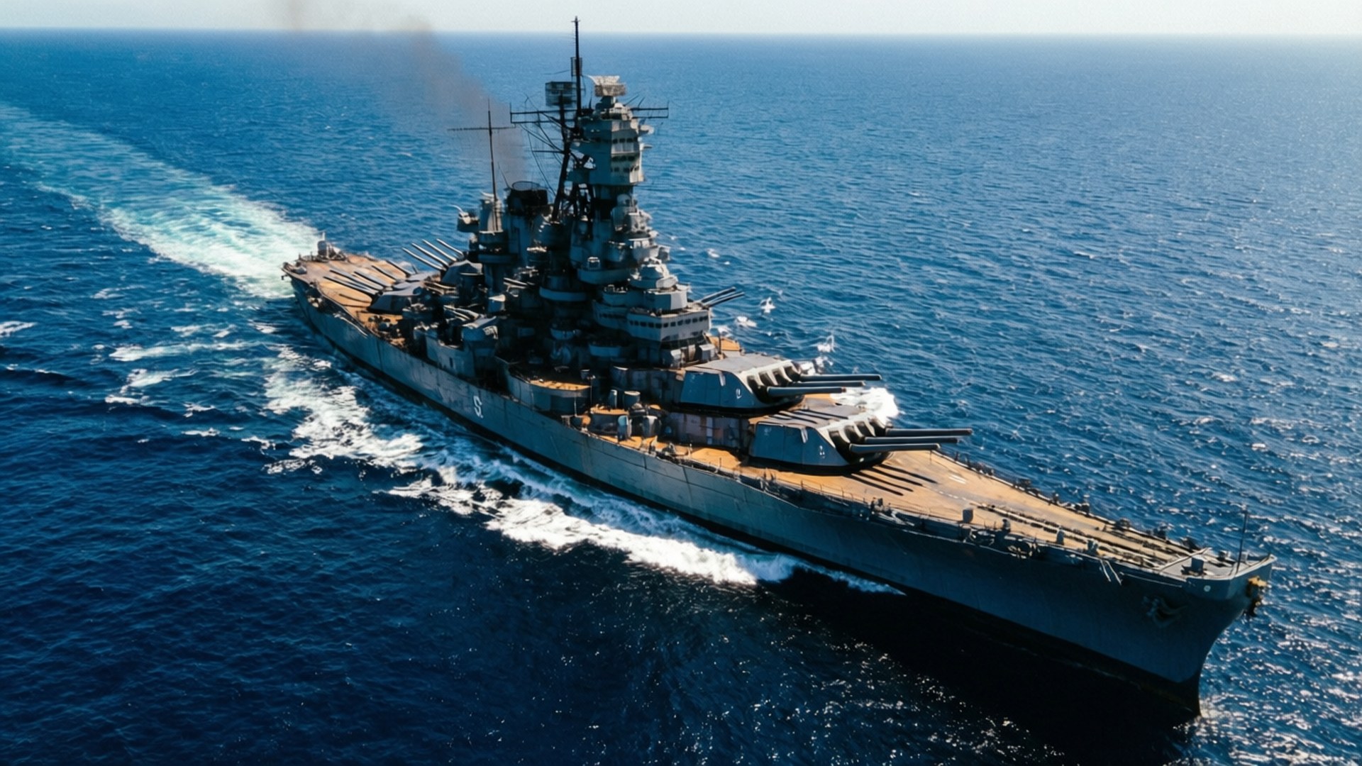 USS Missouri 桌布 壁紙 — 一艘巨大的灰色戰艦劃破深藍色的海浪，在明亮的日光下留下白色的泡沫尾跡。