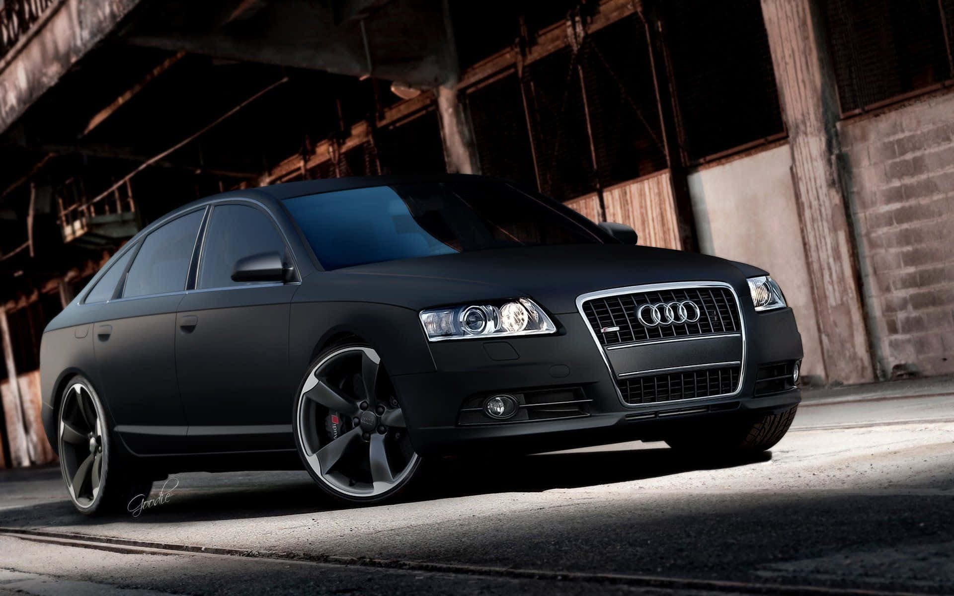 Audi A6 桌布 壁紙 — 一輛消光黑色奧迪轎車配備訂製輪圈，在黃昏時停泊在破舊的工業橋下。
