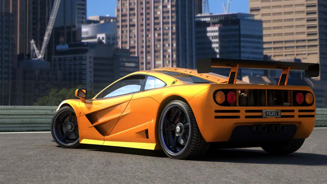 Mclaren F1 桌布 壁紙 — 一輛充滿活力的橙色McLaren F1超級跑車，帶有大型後擾流板，停泊在賽車場上，背景是城市天際線。