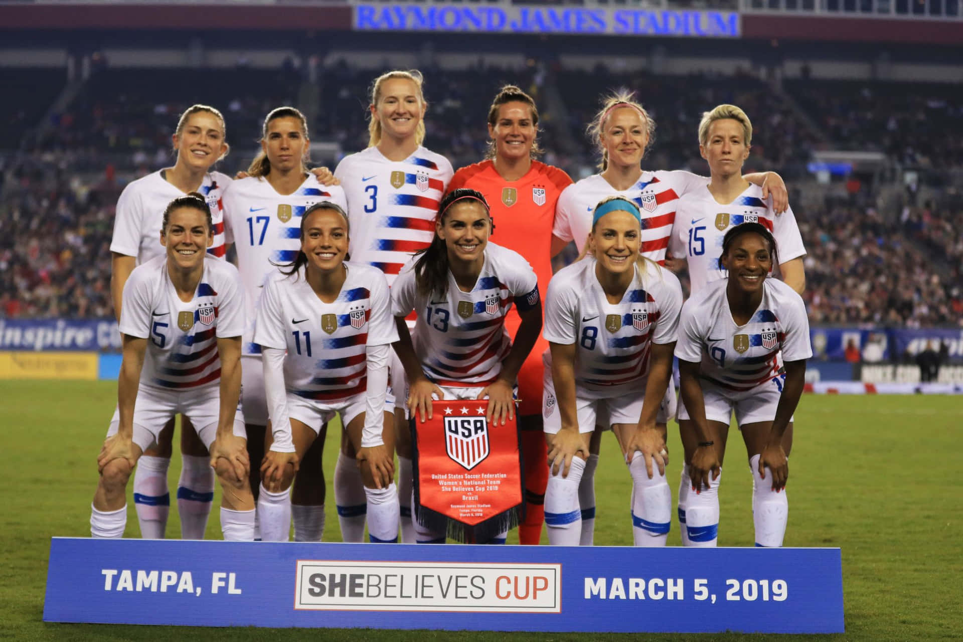  壁紙 — 美國女子足球隊在SheBelieves Cup期間，於夜間球場自豪地穿著愛國球衣擺姿勢。