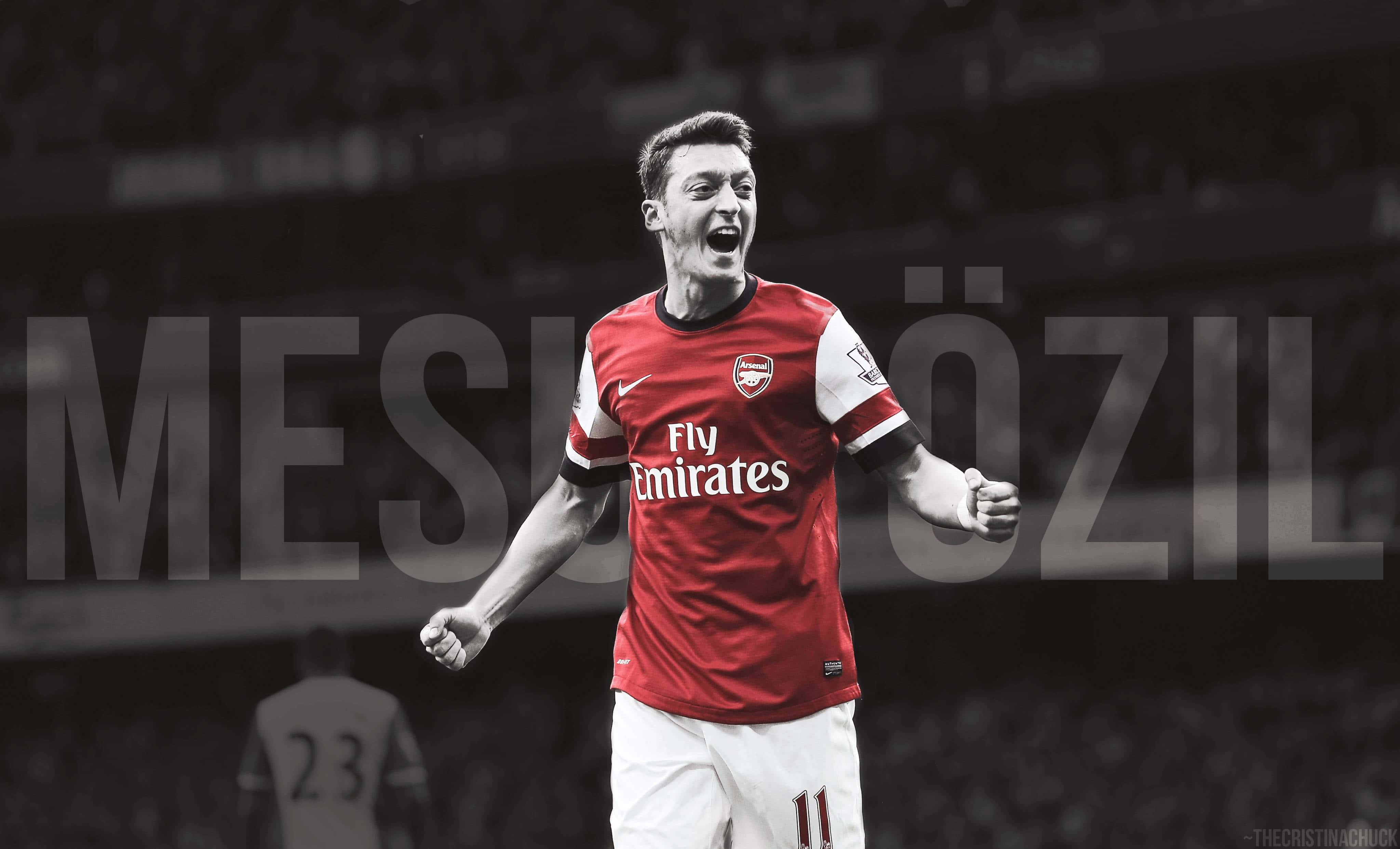 運動 桌布 壁紙 — Mesut Özil 身穿紅色兵工廠球衣，雙臂張開，背景為模糊的球場。
