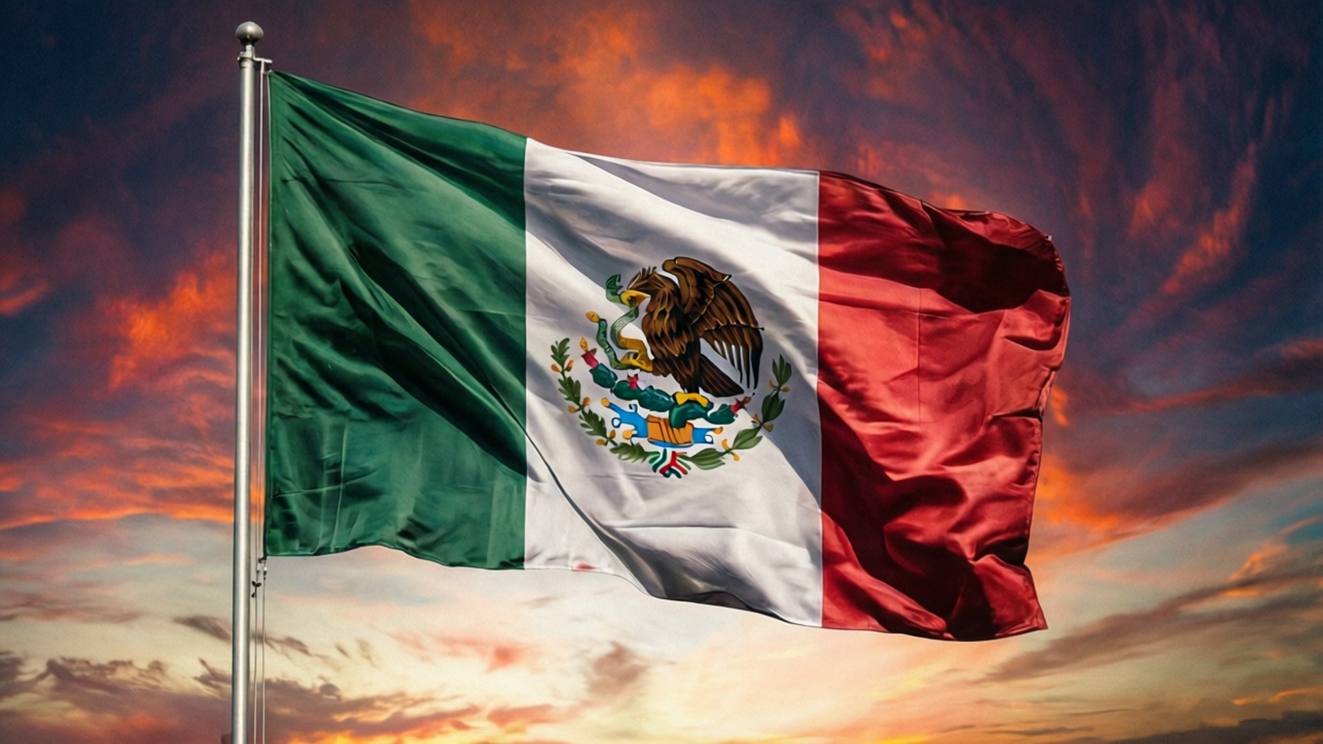 Mexican Flag Sunset 壁紙 — 墨西哥國旗在戲劇性的日落天空下自豪地飄揚，天空中有火橙色和深藍色的雲彩。