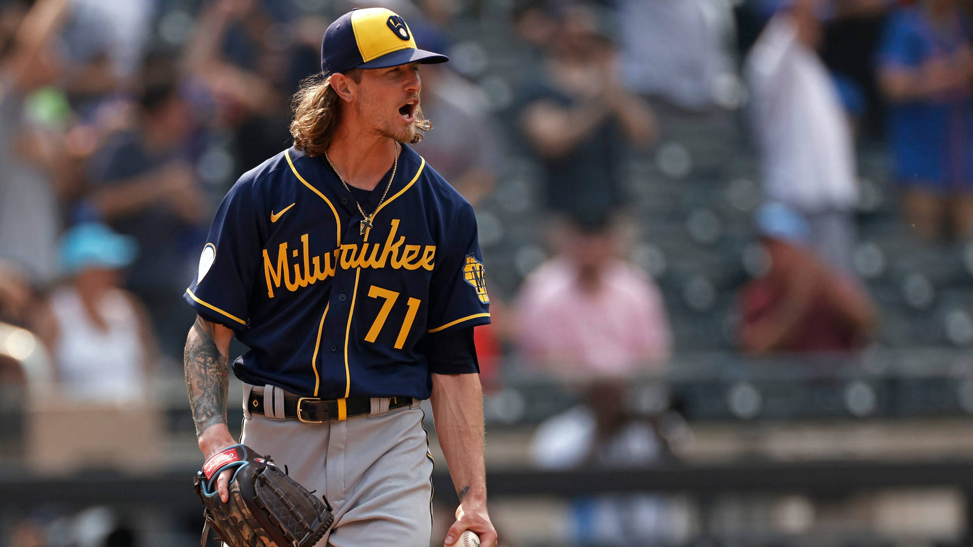 穿著釀酒人隊球衣的棒球運動員在日間比賽中大喊，背景有觀眾。 — MLB 壁紙