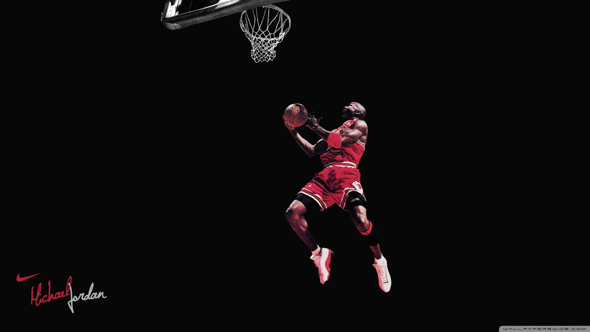 麥可喬丹在半空中身穿紅色球衣灌籃，背景為黑色。 — Jordan Logo 壁紙