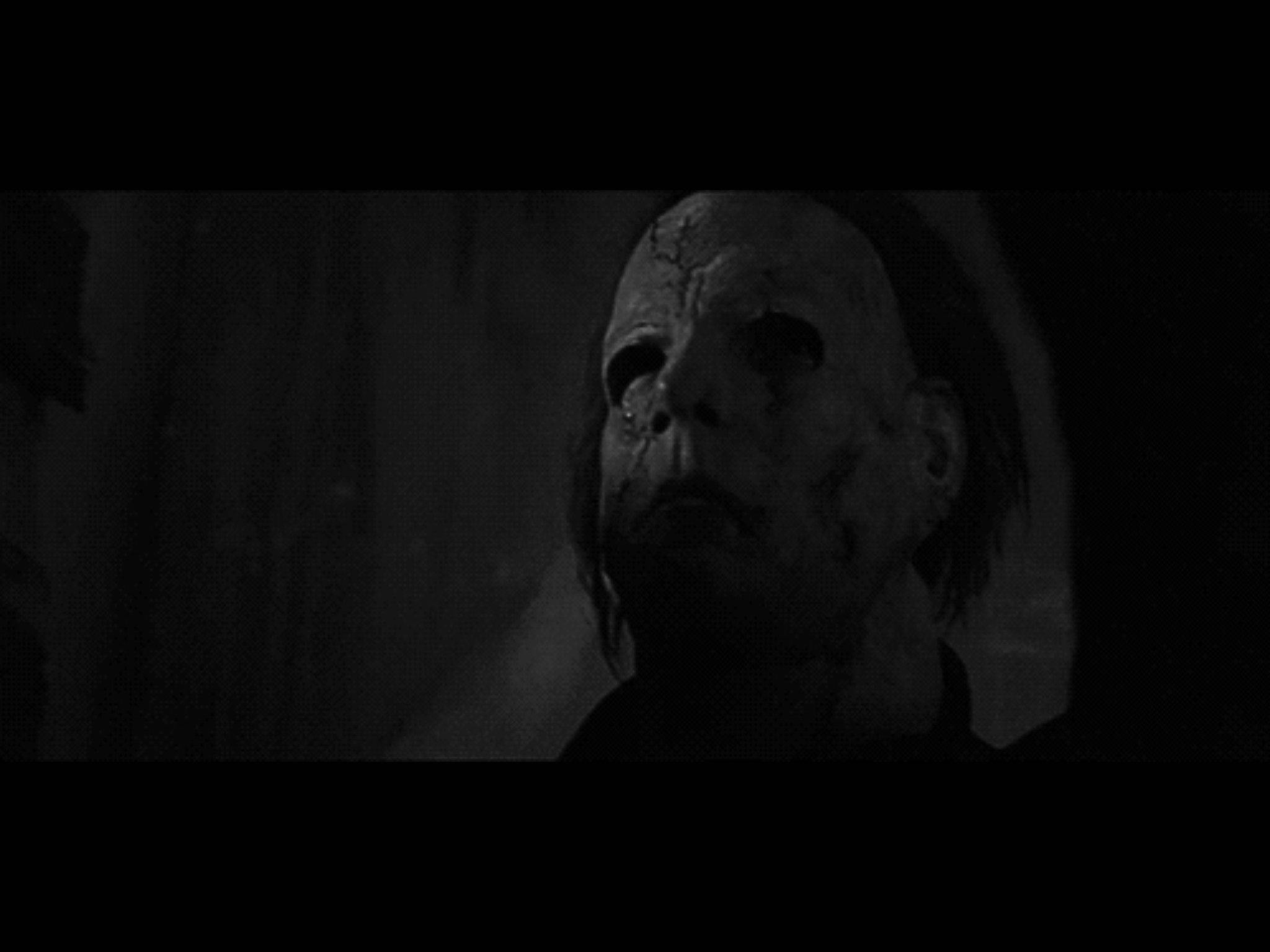 michael 桌布 壁紙 — Michael Myers 戴著其標誌性白色面具的令人毛骨悚然的特寫，在黑暗陰影背景上被強光照射。