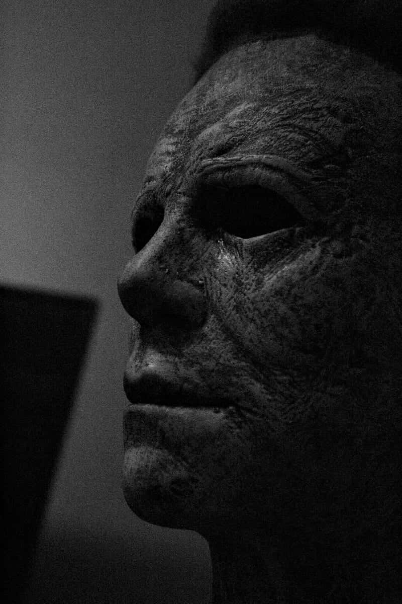萬聖節動圖 桌布 壁紙 — Michael Myers 標誌性傷痕面具在戲劇性側光下的黑白特寫，令人毛骨悚然。