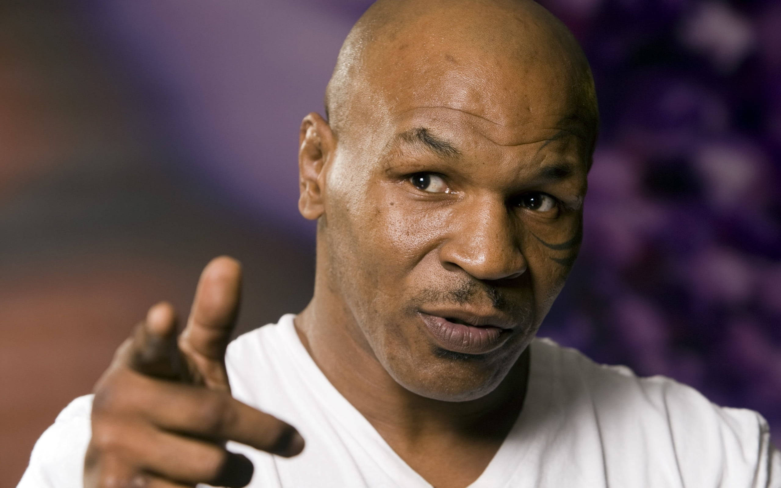 麥克·泰森 桌布 壁紙 — Mike Tyson 直接指向觀眾，眼神強烈，背景為模糊的紫色。