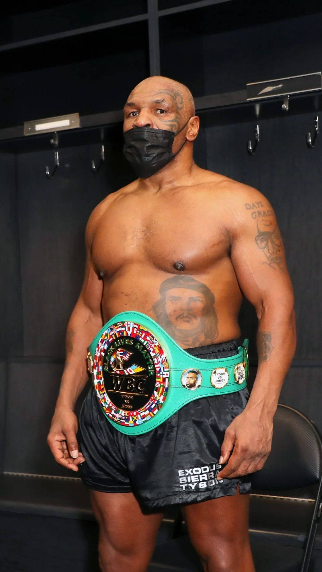 麥克·泰森 桌布 壁紙 — Mike Tyson 站在更衣室，戴著黑色口罩和綠色冠軍腰帶。
