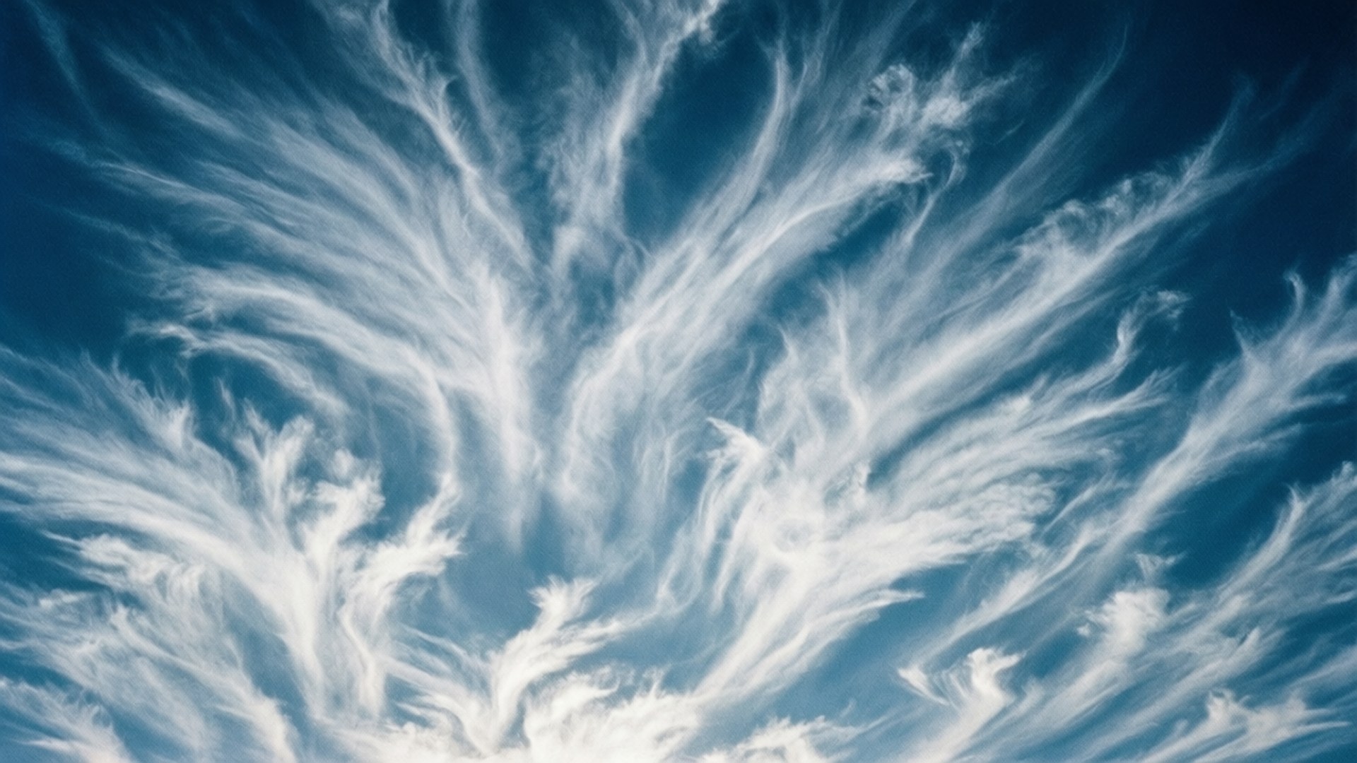 Brush Stroke Clouds 壁紙 — 明亮的白色卷雲在深藍色的天空中形成複雜的羽毛圖案。
