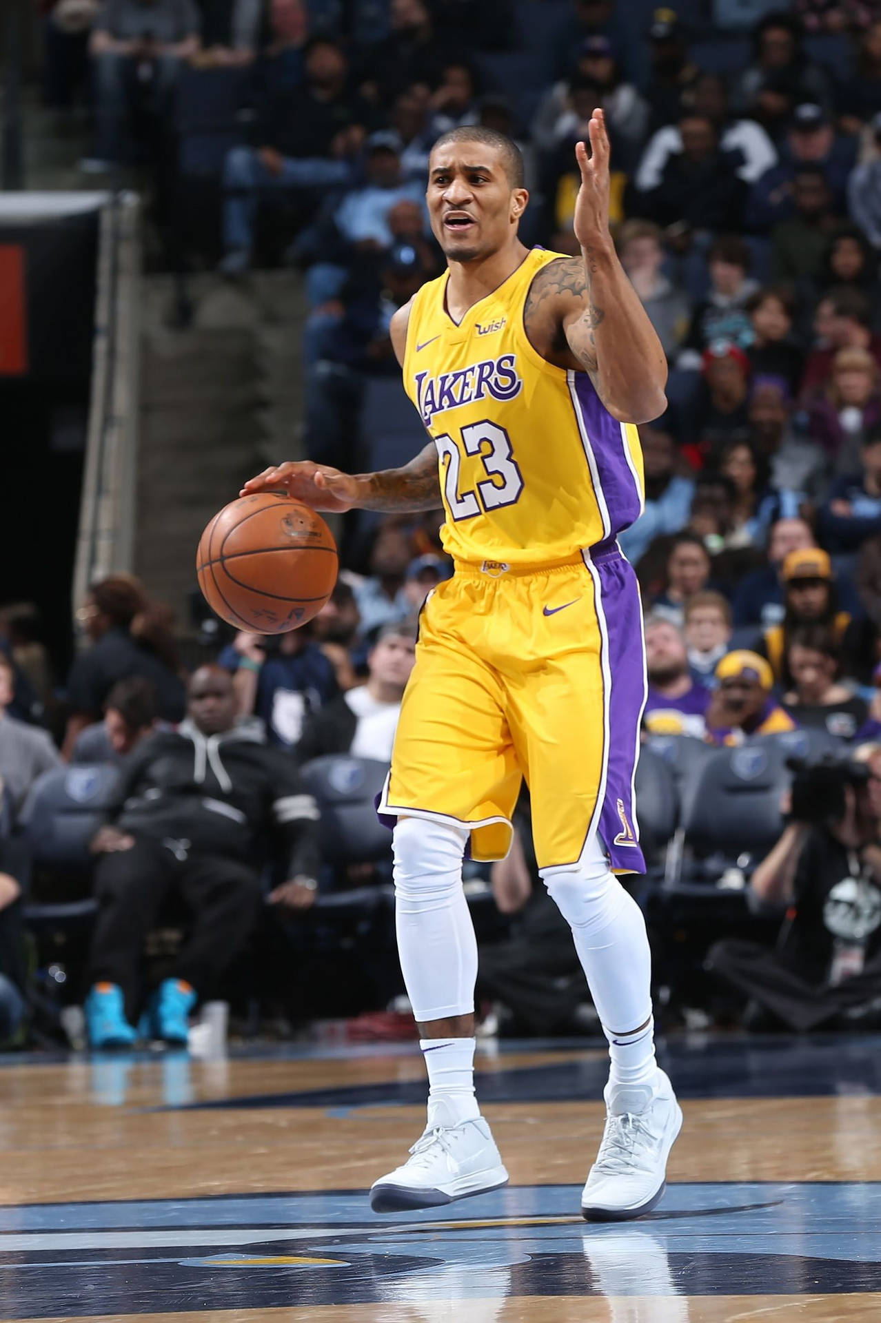 湖人隊籃球運動員在比賽中運球，背景有觀眾。 — NBA 壁紙