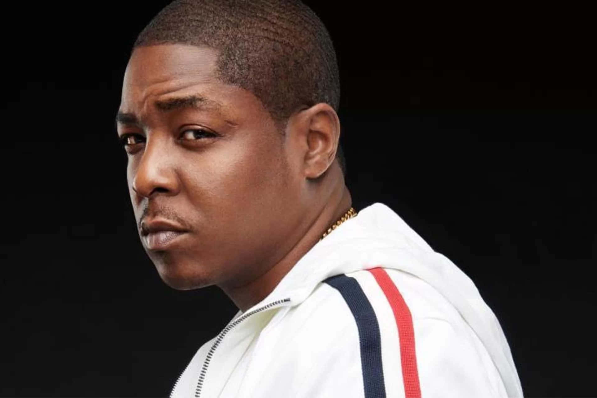  壁紙 — 一名身穿帶有紅色和藍色條紋的白色拉鍊外套的男子，在黑色背景前專注地凝視。