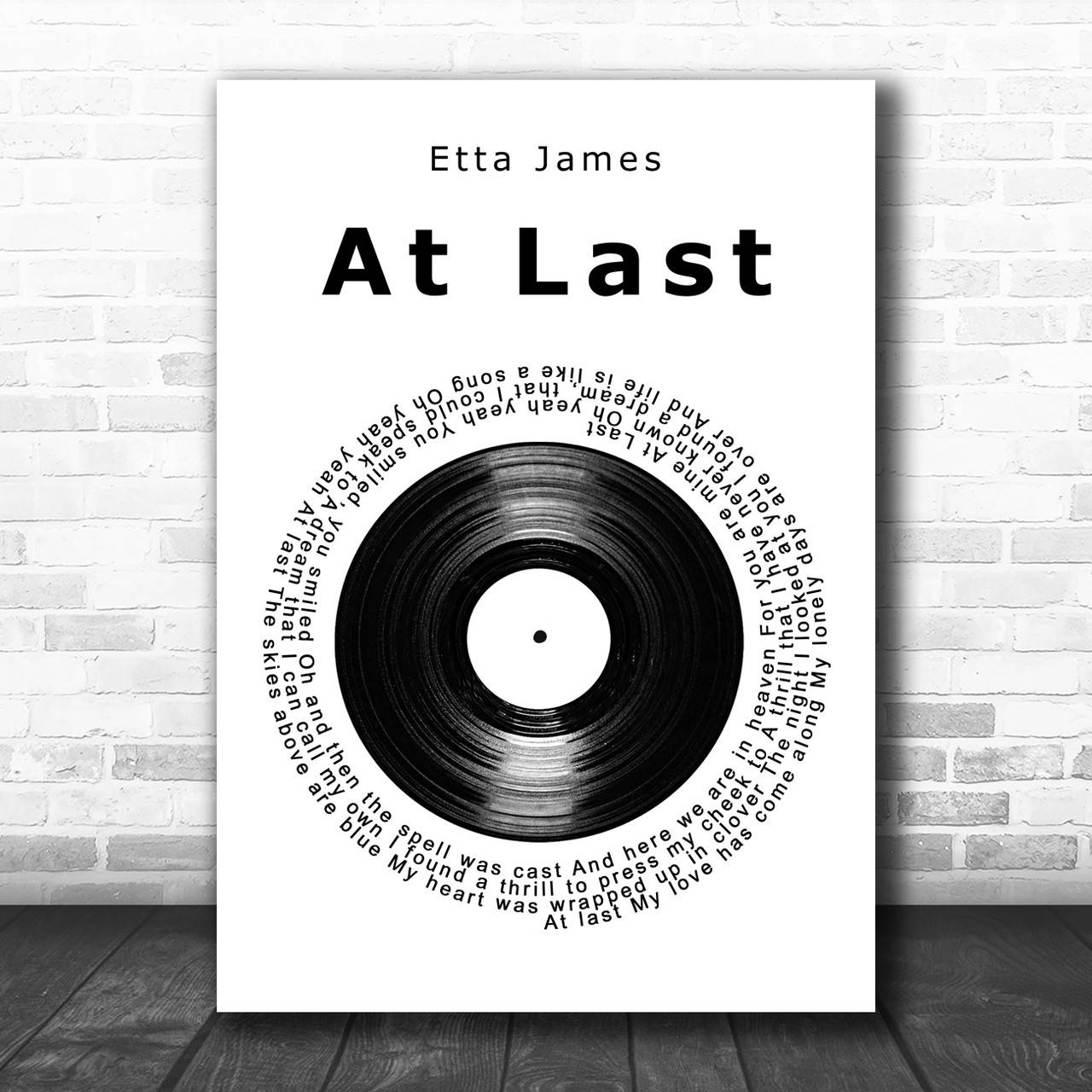 黑白 桌布 壁紙 — Etta James《At Last》的極簡黑白海報，歌詞圍繞黑膠唱片形成圓圈，掛在白色磚牆上，下方是深色木地板。