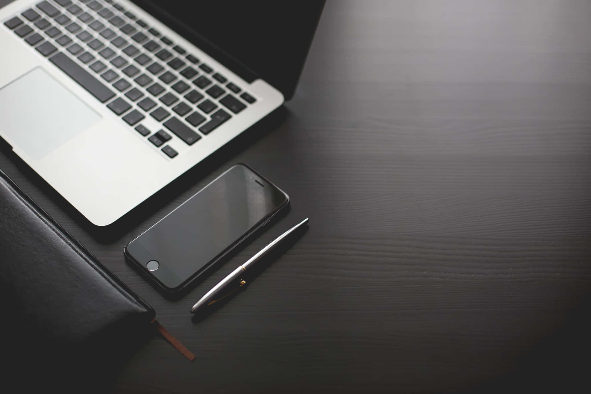 深色木桌上的銀色筆記型電腦、智慧型手機和筆 — Macbook Pro 壁紙