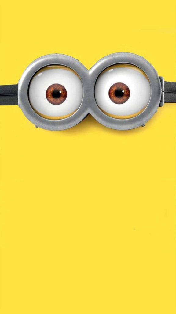 搞笑 iPhone 桌布 壁紙 — Minion 的大圓形護目鏡特寫，棕色眼睛襯托純黃色背景。