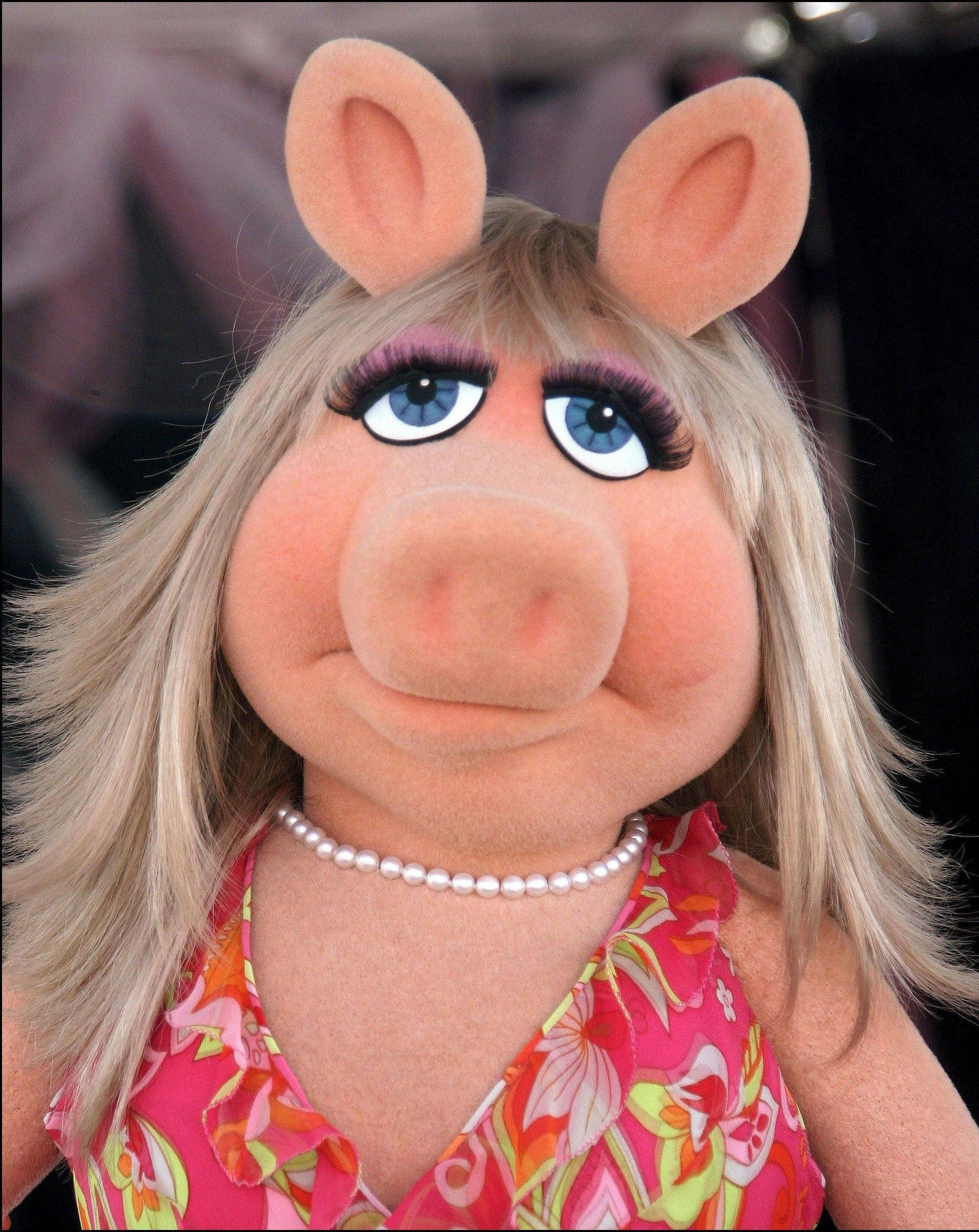Miss Piggy 桌布 壁紙 — Miss Piggy 的特寫，金髮藍眼粉紅色耳朵，穿著花卉圖案上衣和珍珠項鍊。