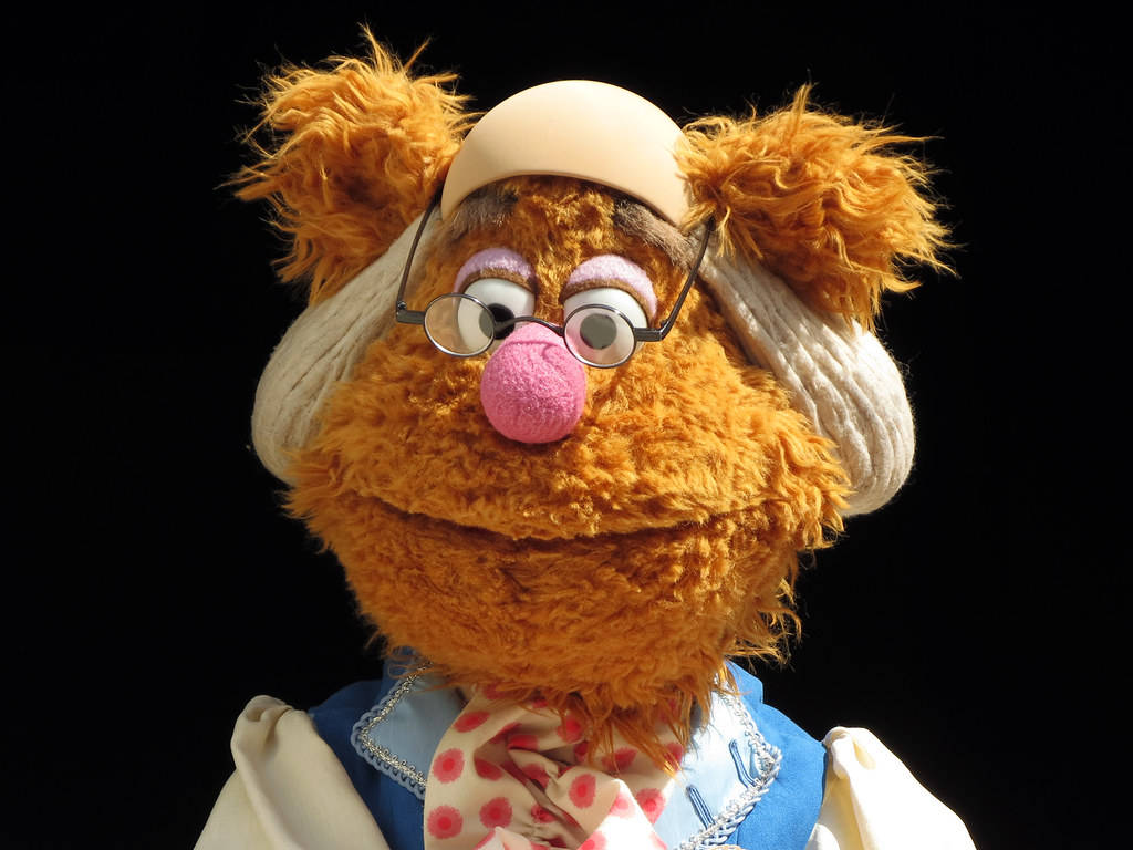 Fozzie Bear 桌布 壁紙 — Miss Piggy 近照，身穿護士服，戴眼鏡，粉紅色鼻子，黑色背景。