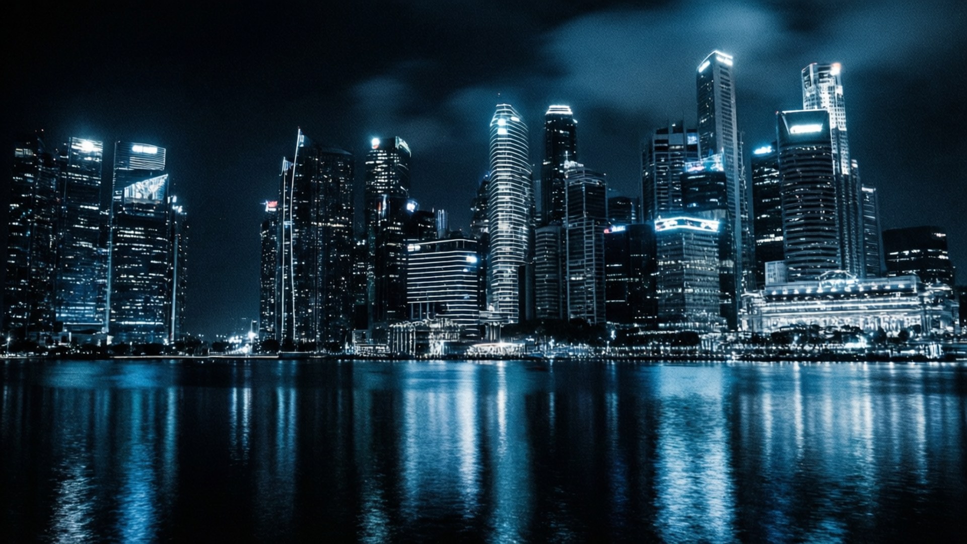 Duotone 桌布 壁紙 — 現代城市天際線的壯麗夜景，高聳的摩天大樓在黑暗天空下倒映在平靜的水面上。