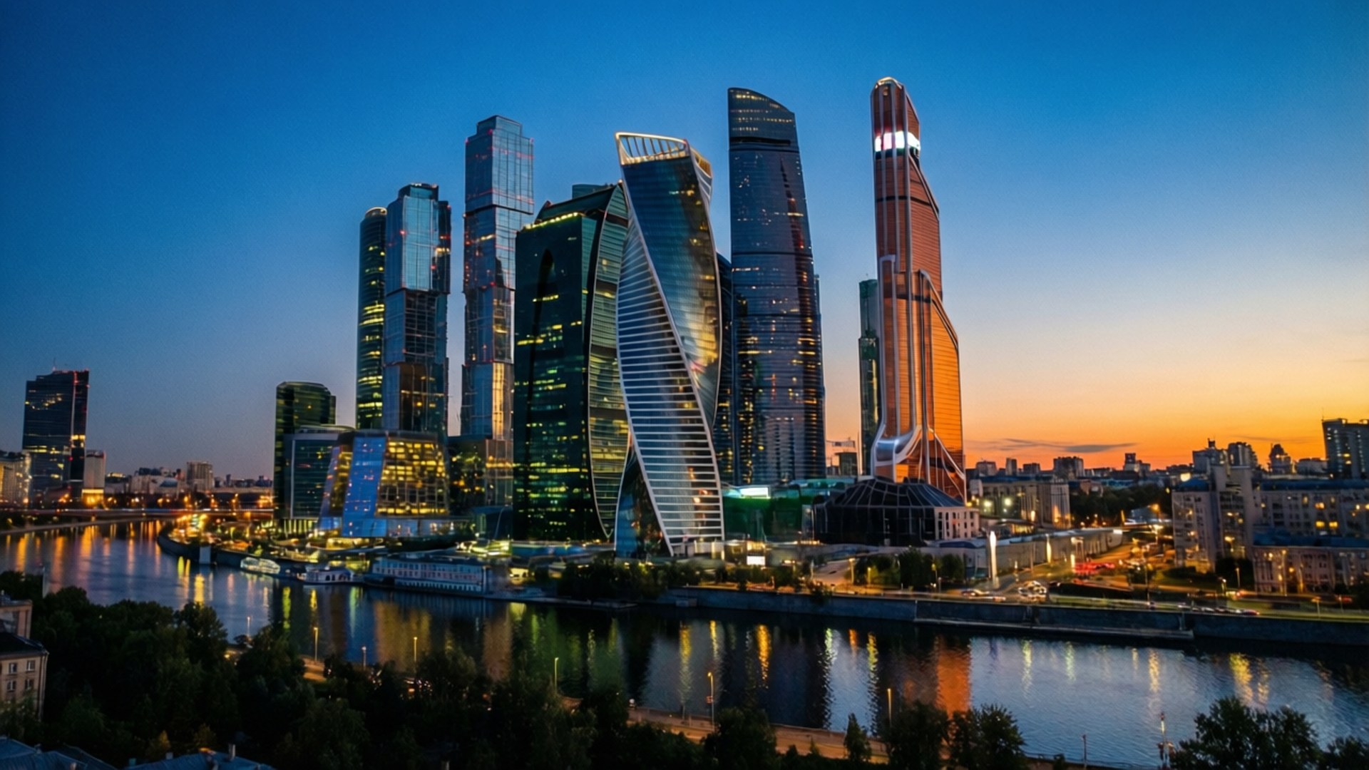 Moscow City Skyline 壁紙 — 現代玻璃摩天大樓在黃昏時分，在繁華城市中平靜的河面上反射出金色的日落色調。
