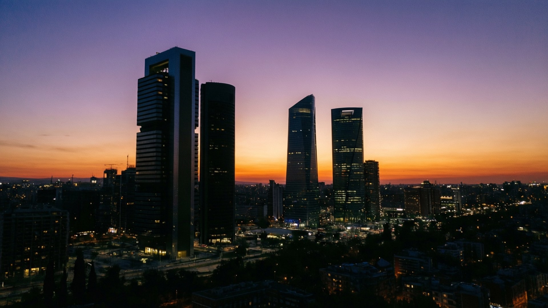 Cuatro Torres Dusk Skyline 壁紙 — 現代摩天大樓的剪影，映襯著繁忙城市上空充滿活力的紫橙色日落天空。