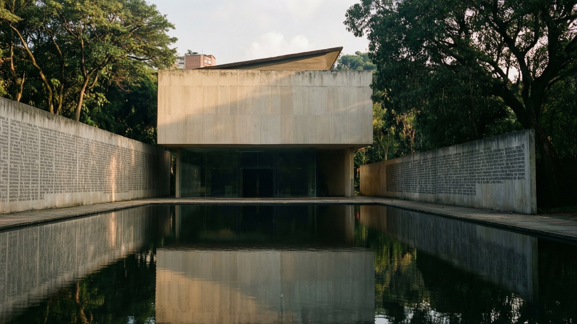 Memory House Museum 壁紙 — 一座現代主義混凝土建築，帶有玻璃門，矗立在反射池的盡頭，兩側是雕刻牆壁和茂密的綠色樹木。