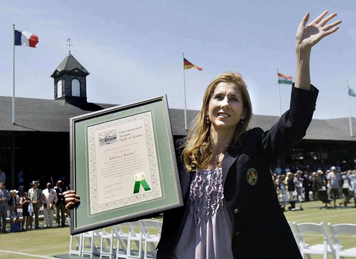 Monica Seles 桌布 壁紙 — Monica Seles 在陽光明媚的網球場上高興地揮舞著她的國際網球名人堂獎牌。