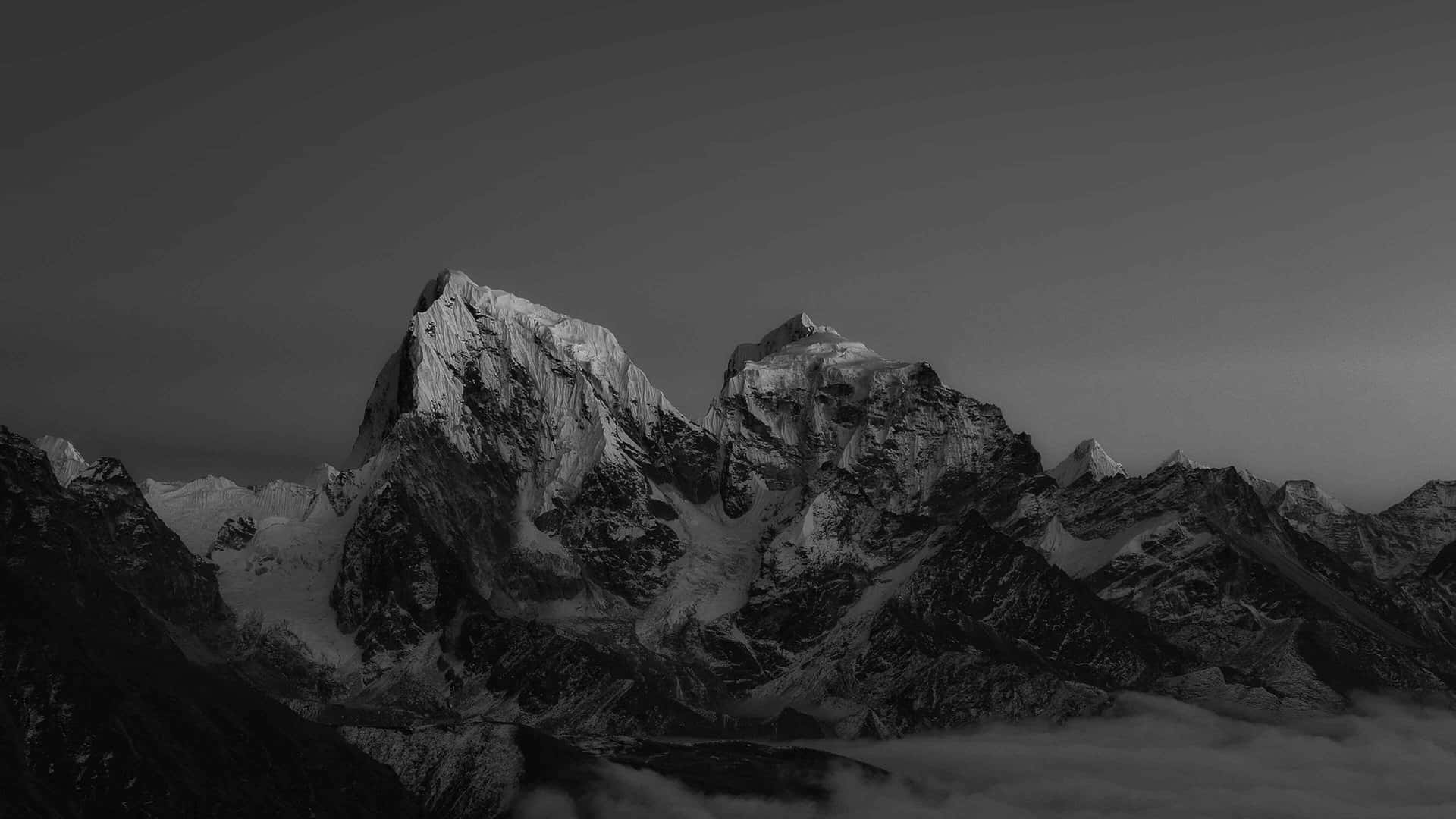  壁紙 — 單色山峰穿透霧雲，在漸變天空下。
