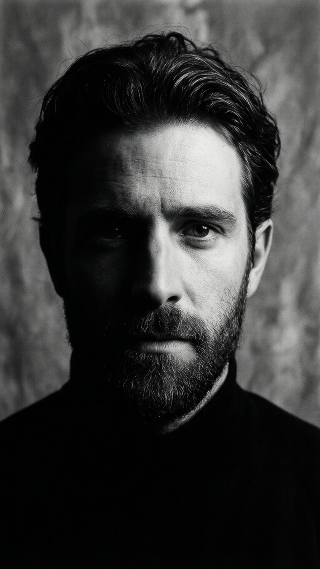 Shadow Portrait 壁紙 — 一個鬍鬚男的黑白肖像，眼神強烈，背景有紋理，氣氛陰沉。