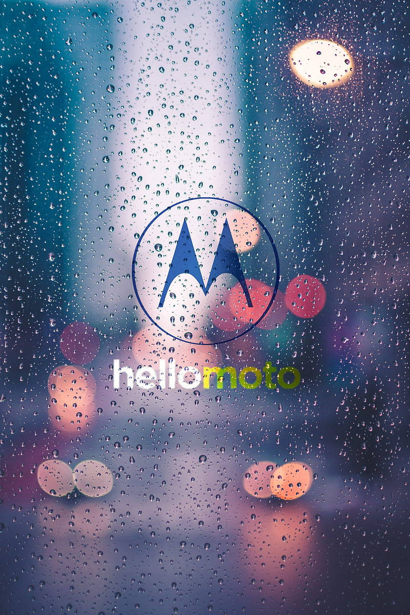 摩托羅拉 桌布 壁紙 — Motorola 標誌在濺滿雨水的窗戶中發光，背景是模糊的城市燈光。