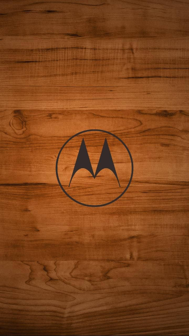 摩托羅拉 桌布 壁紙 — Motorola 標誌在黑色圓圈中，置於溫暖棕色木紋壁紙中央。