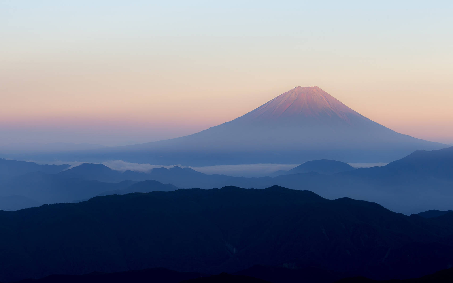 黎明時分的富士山，粉紅色和藍色的天空，霧氣繚繞的山巒層次。 — 富士山 壁紙