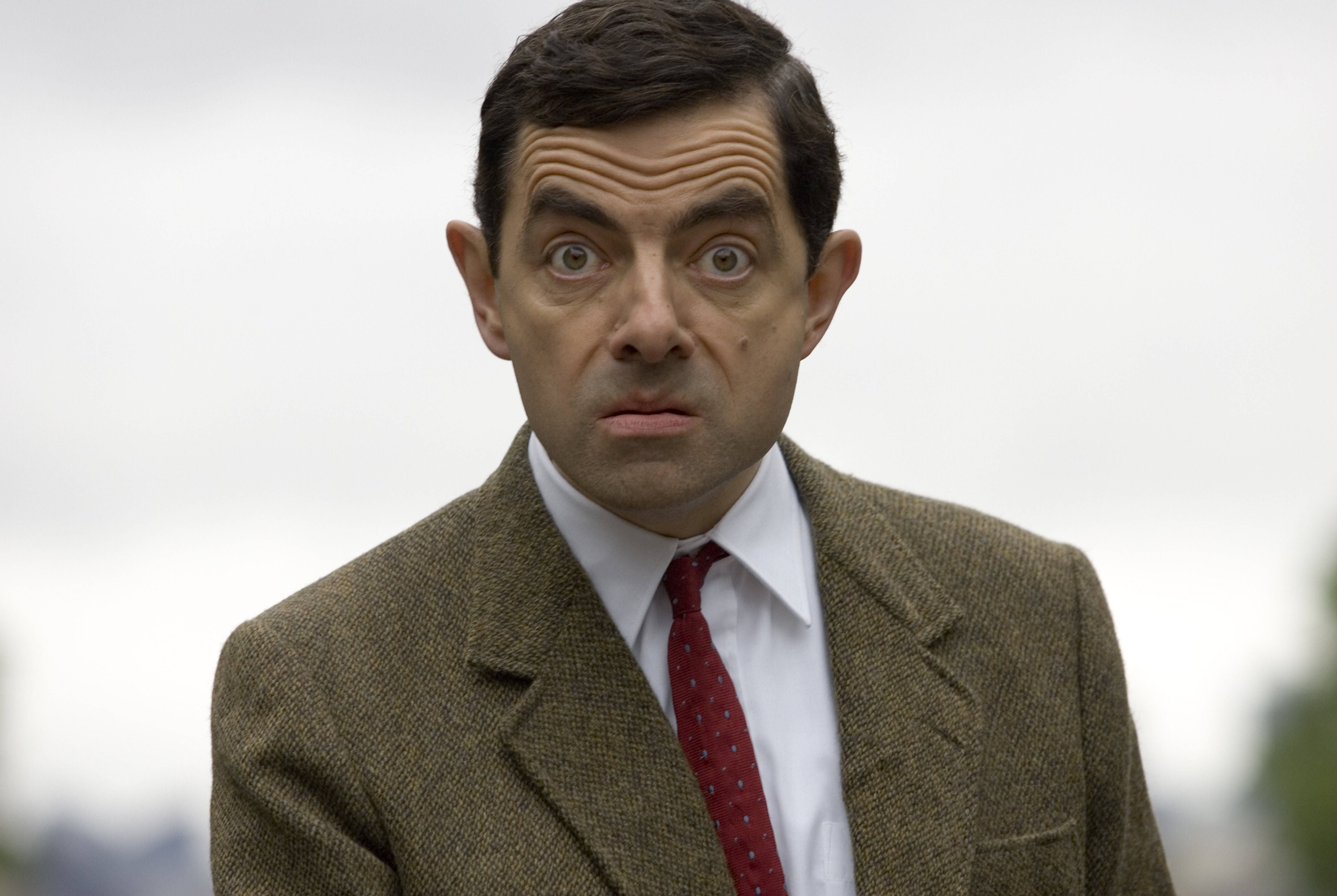 身穿棕色粗花呢西裝和紅色領帶、表情震驚的 Mr Bean。 — 4K 壁紙