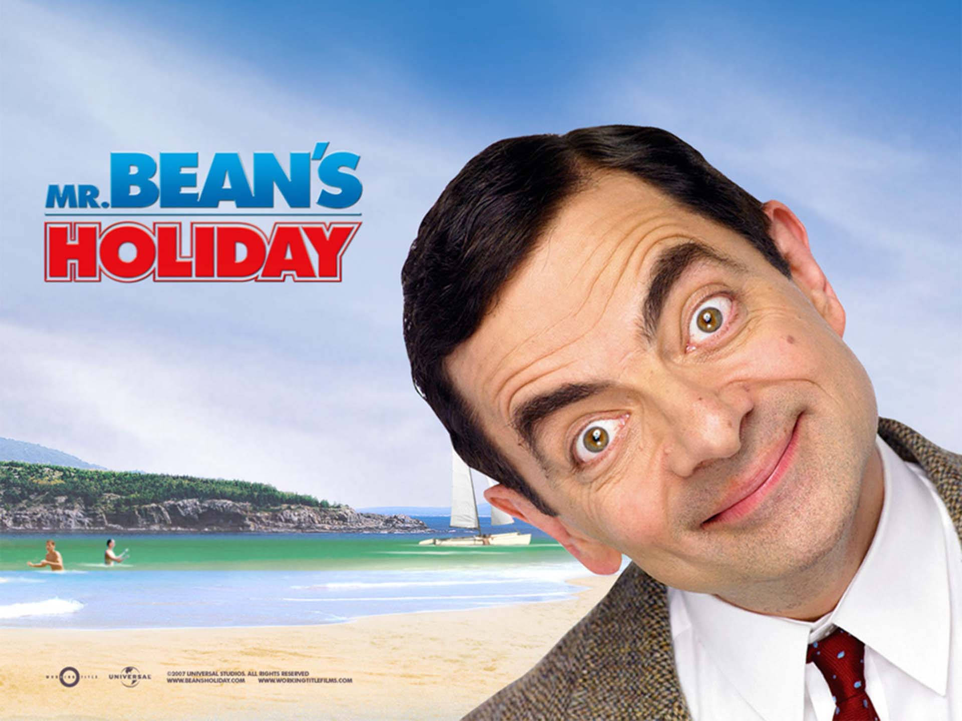 豆豆先生 桌布 壁紙 — Mr Bean 在陽光明媚的海灘背景下，背景有帆船和游泳者，頑皮地咧嘴笑。
