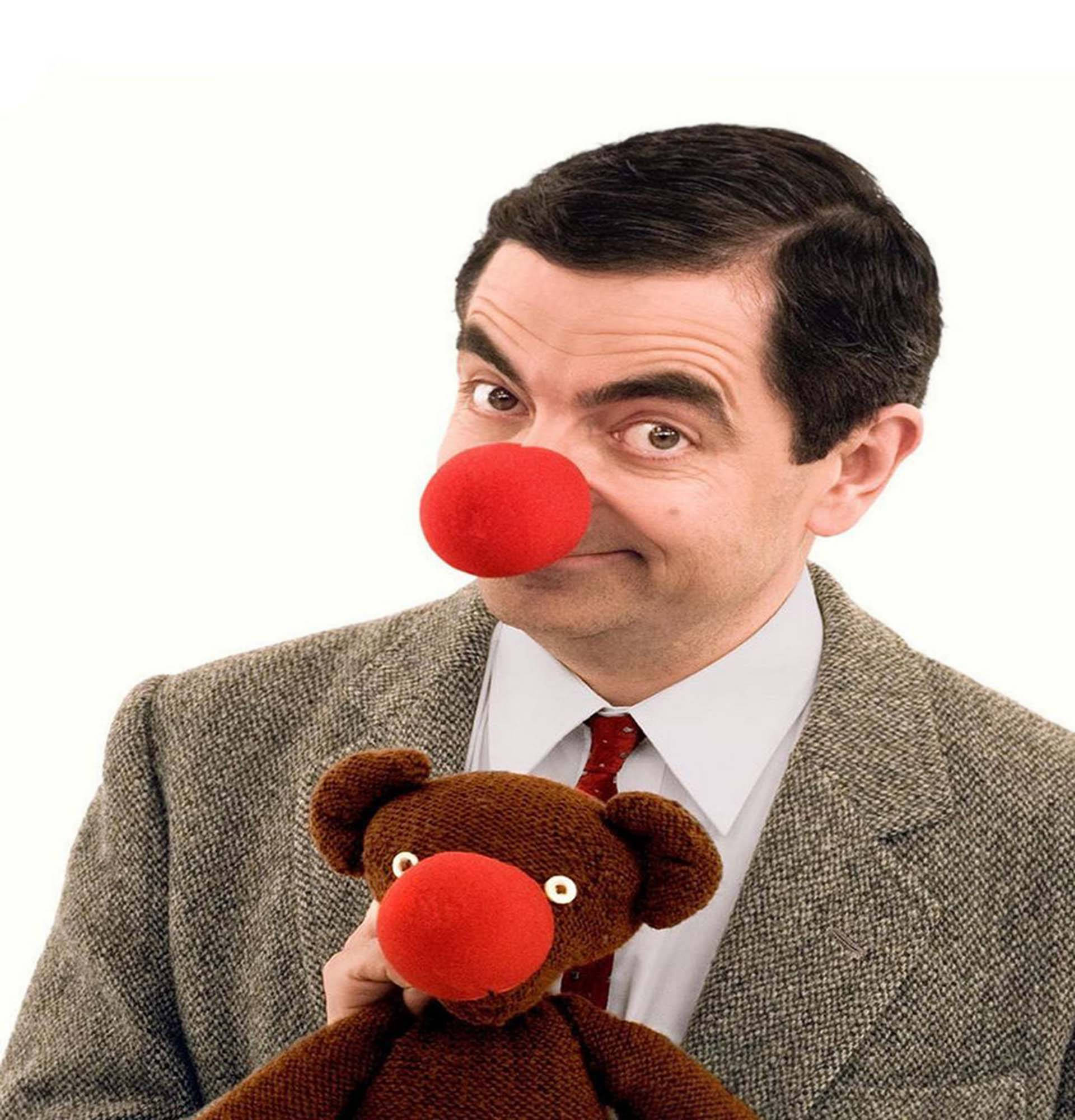 Mr Bean 桌布 壁紙 — Mr Bean 戴著紅色小丑鼻，手持一個同樣有紅色鼻子的泰迪熊，背景為純白色。