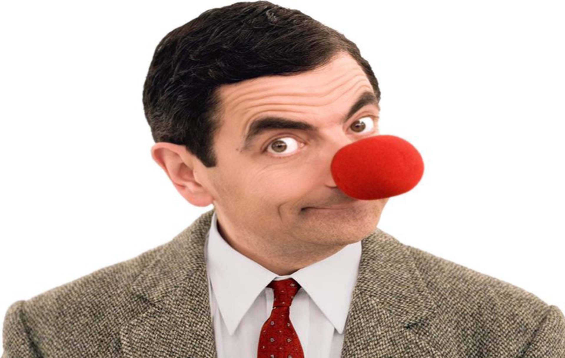 豆豆先生 桌布 壁紙 — Mr. Bean 戴著紅色小丑鼻子，穿著正式西裝，在純白背景前瞪大眼睛凝視。