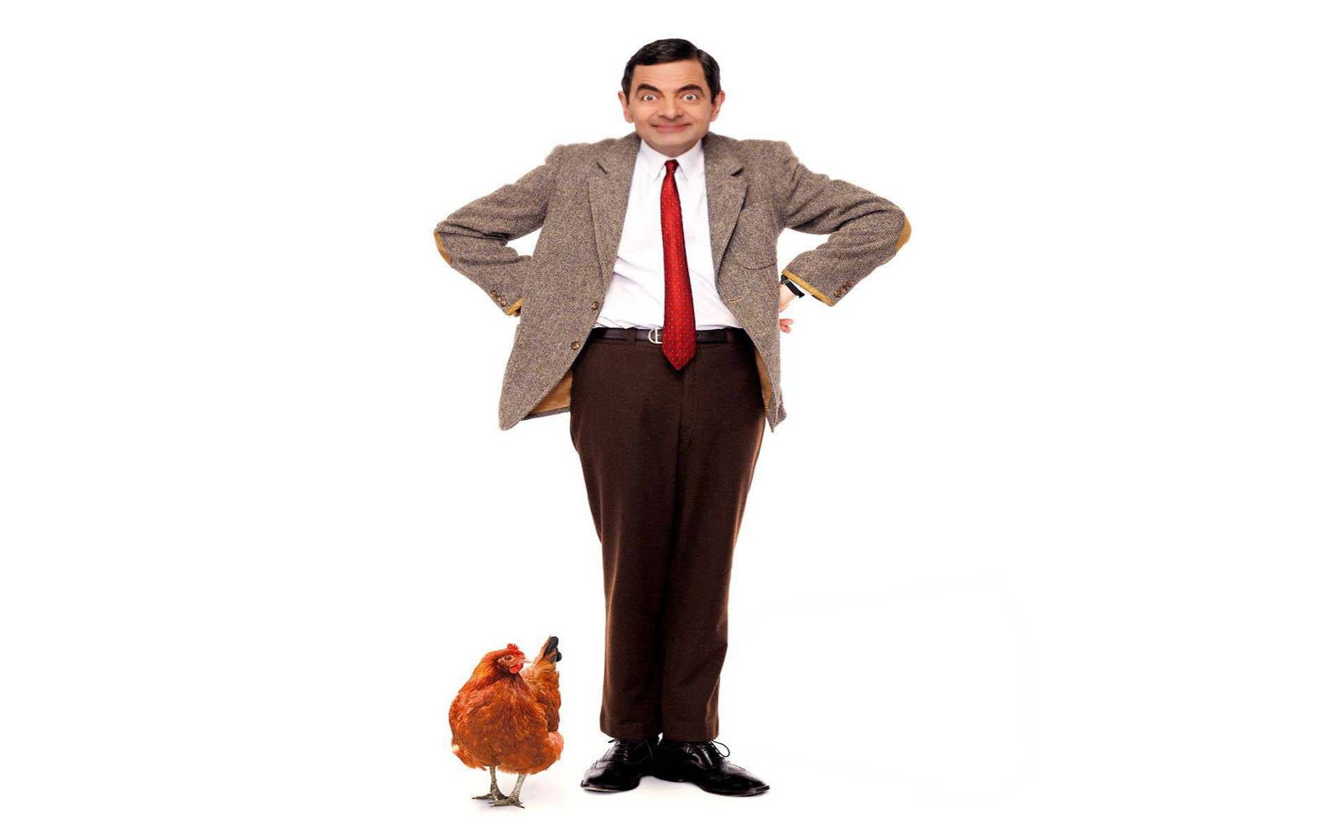 Mr Bean 桌布 壁紙 — Mr. Bean 自信地雙手叉腰，站在一隻小棕色雞旁邊，背景是純白色。