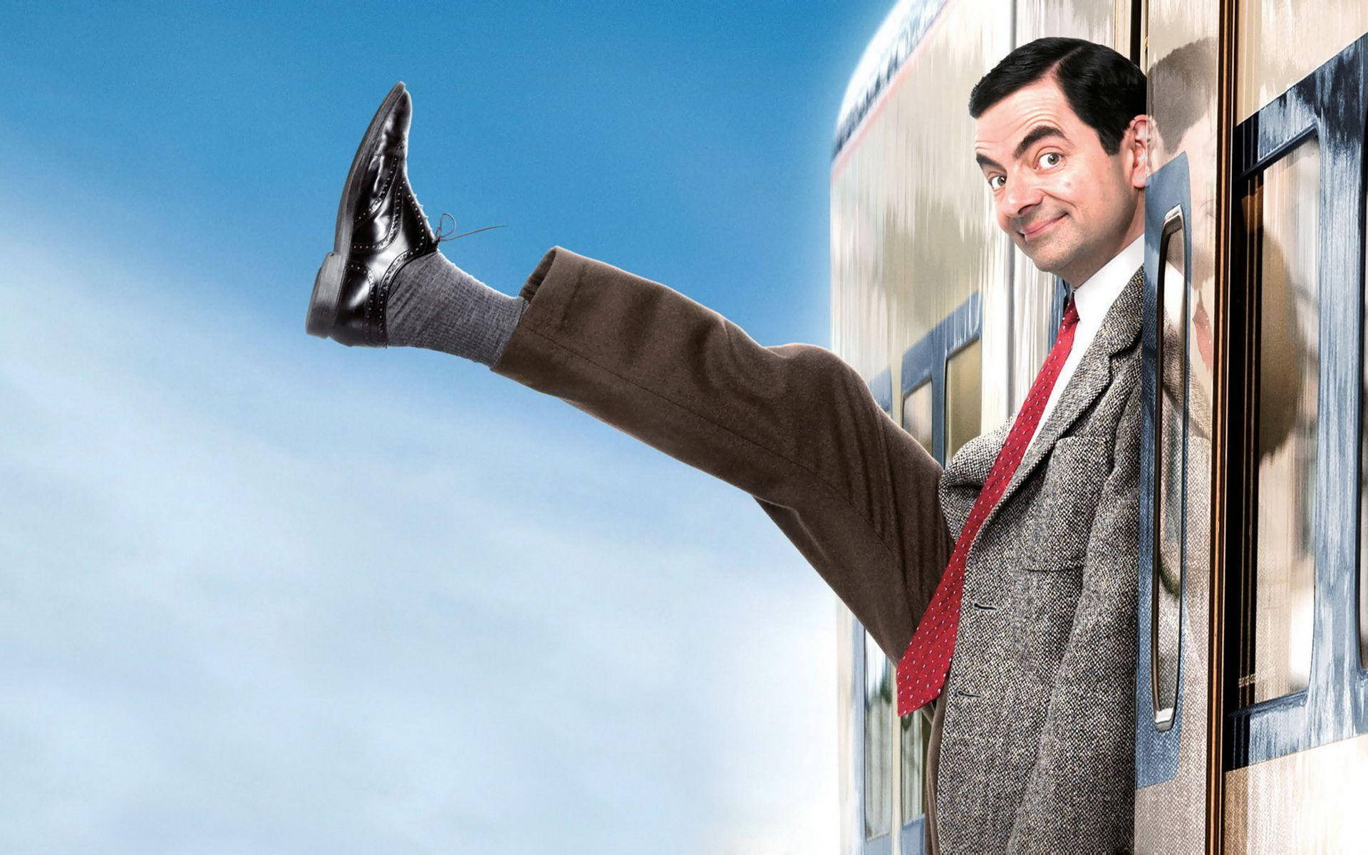 豆豆先生 桌布 壁紙 — Mr. Bean 頑皮地將腿伸出火車窗外，背景是明亮的藍天。