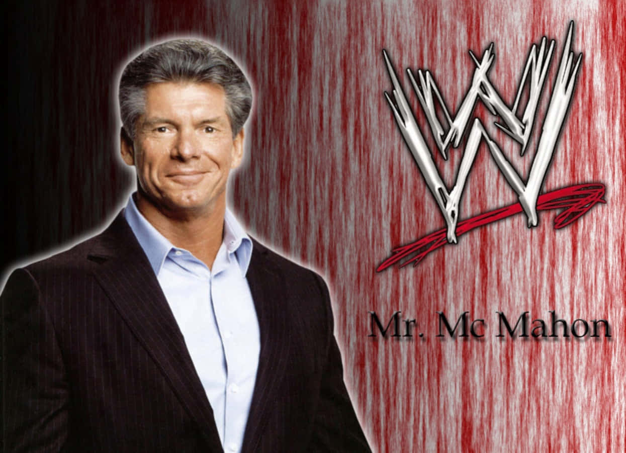 WWE 桌布 壁紙 — Mr McMahon 身穿深色西裝，在帶有WWE標誌的紅色紋理背景上微笑。