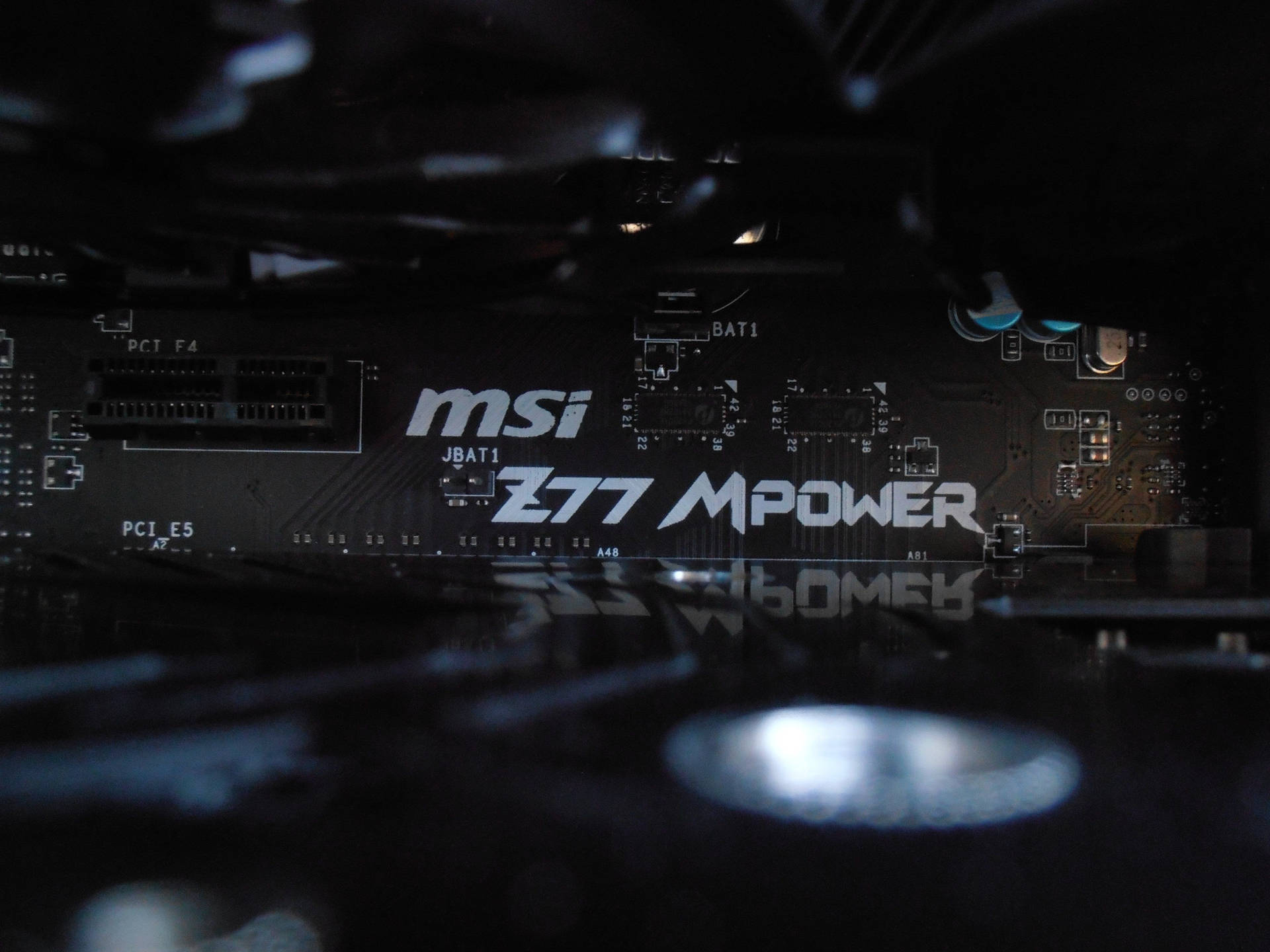 黑色 MSI Z77 MPower 主機板特寫，帶有藍色電容和白色文字。 — 1920x1080 4K 壁紙