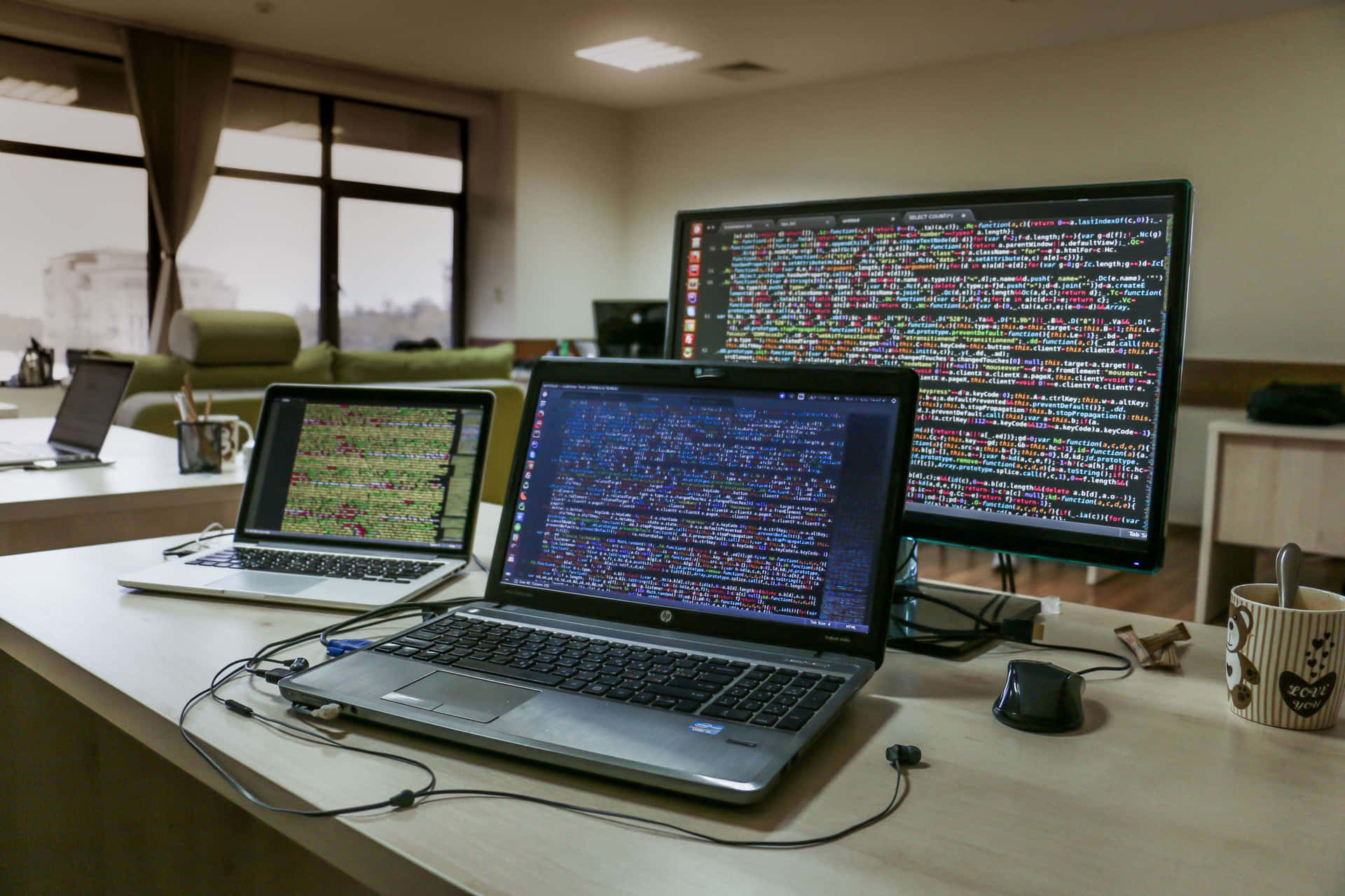 筆記型電腦和顯示器在家庭辦公室的木桌上顯示程式碼。 — Valorant 4K 壁紙 壁紙
