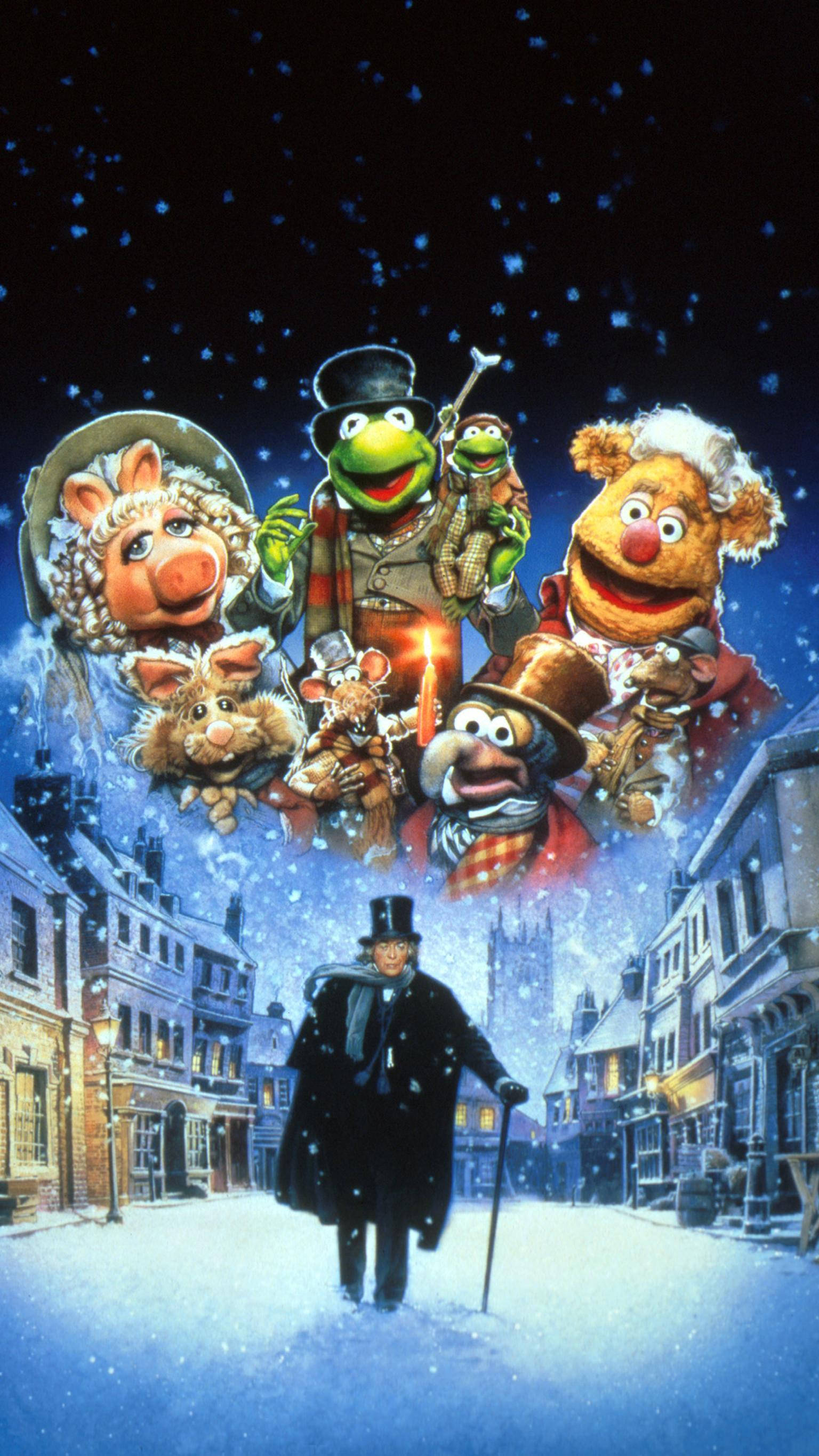 A 桌布 壁紙 — Muppet 角色愉快地漂浮在白雪覆蓋的維多利亞式街道上方，一名男子在飄雪下行走於下方。