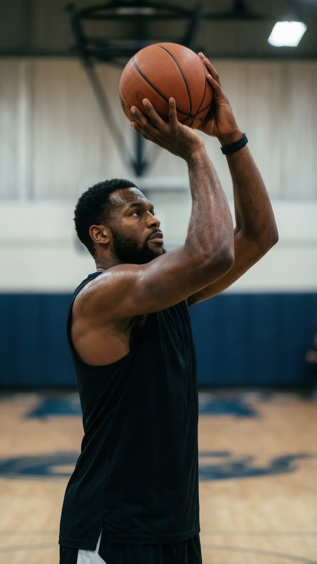 Free Throw Routine 壁紙 — 一位肌肉發達的籃球運動員穿著黑色背心，在室內體育館用雙手投籃。