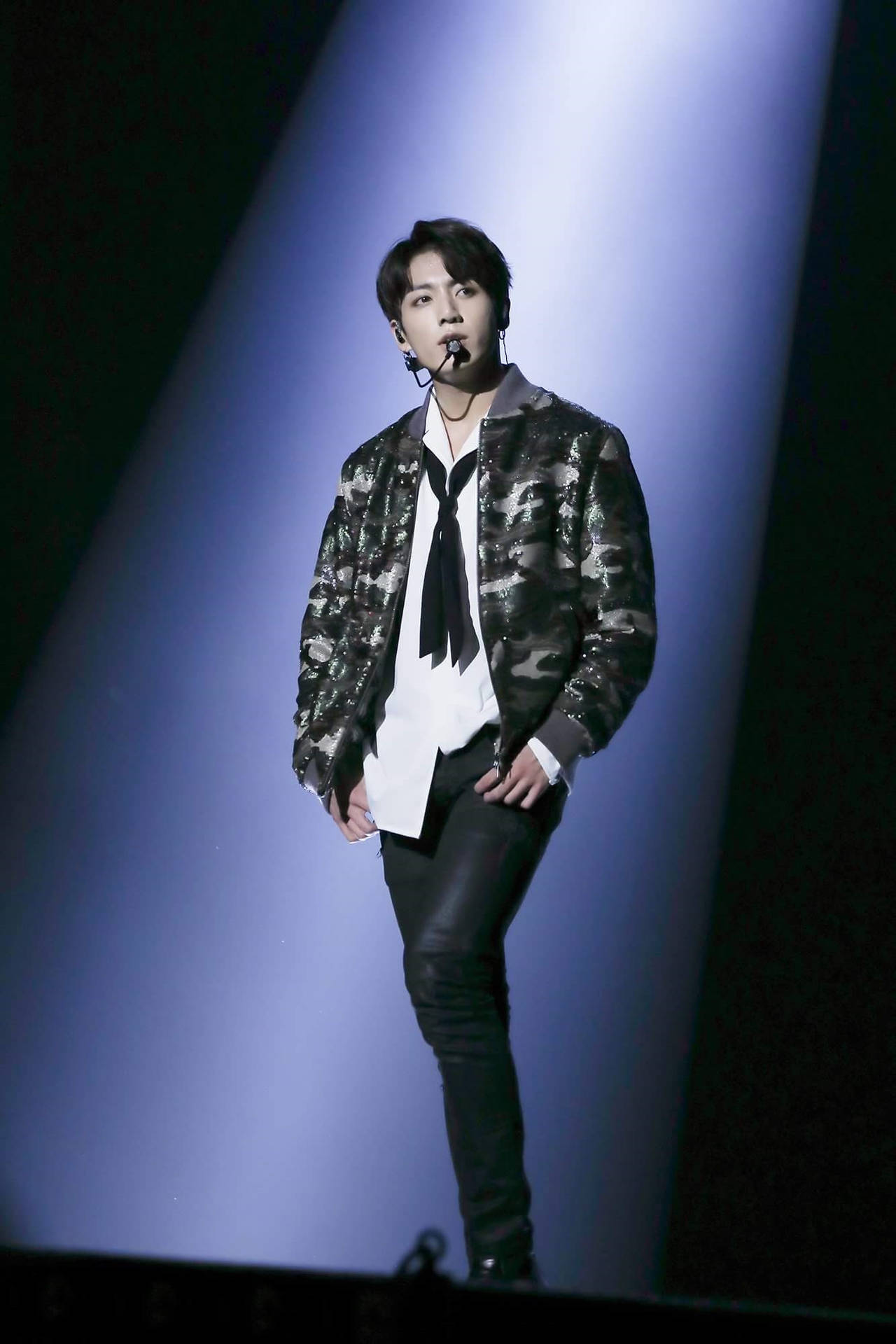 男性表演者在舞台上，身穿迷彩外套和黑色褲子，處於聚光燈下。 — Bts 壁紙