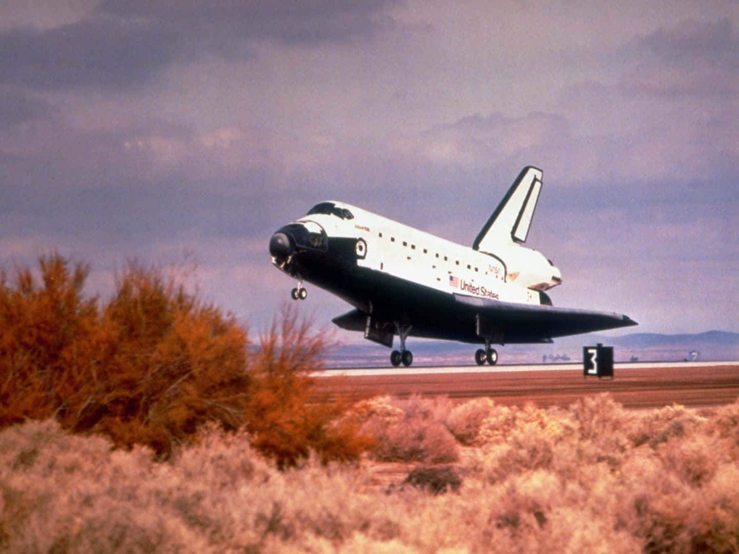 Aircraft 桌布 壁紙 — NASA 太空梭在陰天下降落在被沙漠灌木環繞的跑道上。