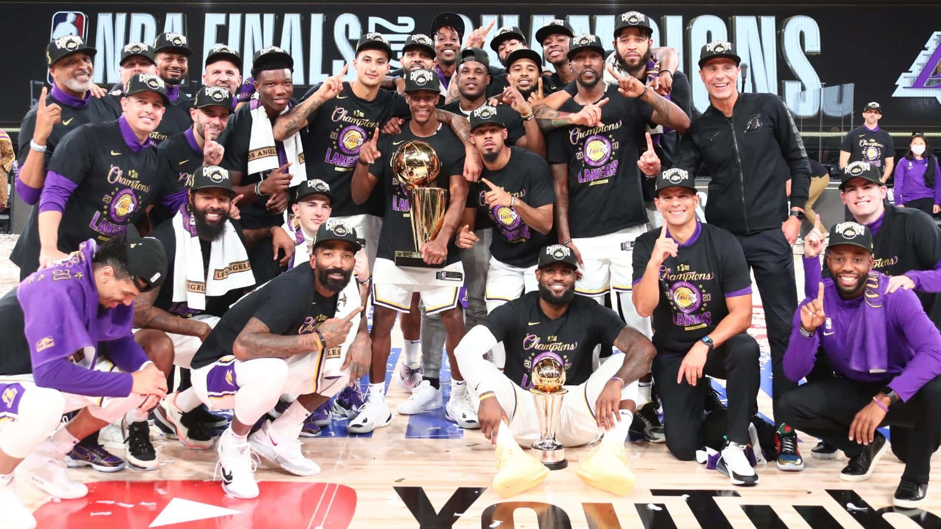  壁紙 — NBA冠軍湖人隊在球場上穿著紫色和金色球衣慶祝獎盃。